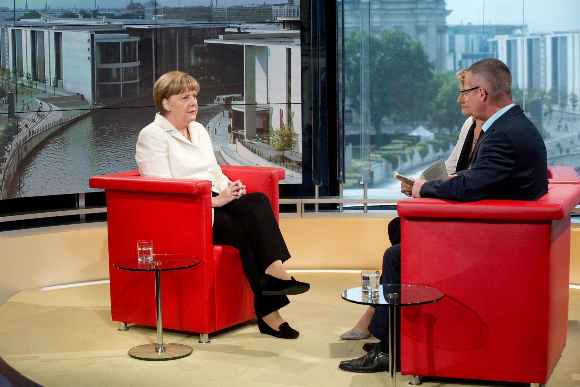 epa04853339 German Chancellor Angela Merkel (L) is interviewed by journalists Tina Hassel (not pictured) and Rainald Becker (R) at the German television channel ARD main studios in Berlin, Germany, 19 July 2015.  EPA/JOERG CARSTENSEN