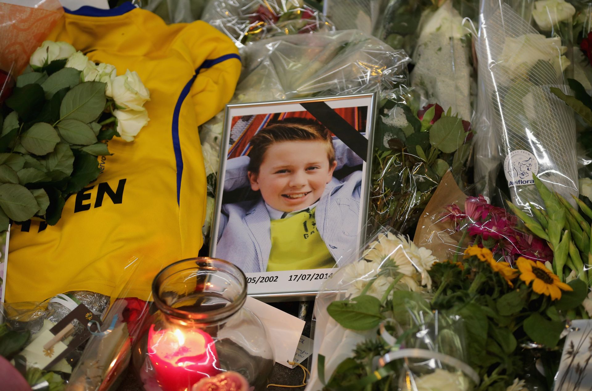 AMSTERDAM, NETHERLANDS - JULY 20:  A photograph of a young boy lies amongst tributes at the entrance to Schiphol Airport which has grown into a sea of flowers in memory of the victims of Malaysia Airlines flight MH17 on July 20, 2014 in Amsterdam, Netherlands.  Malaysian Airlines flight MH17 was travelling from Amsterdam to Kuala Lumpur when it crashed killing all 298 on board including 80 children. The aircraft was allegedly shot down by a missile and investigations continue over the perpetrators of the attack.  (Photo by Christopher Furlong/Getty Images)