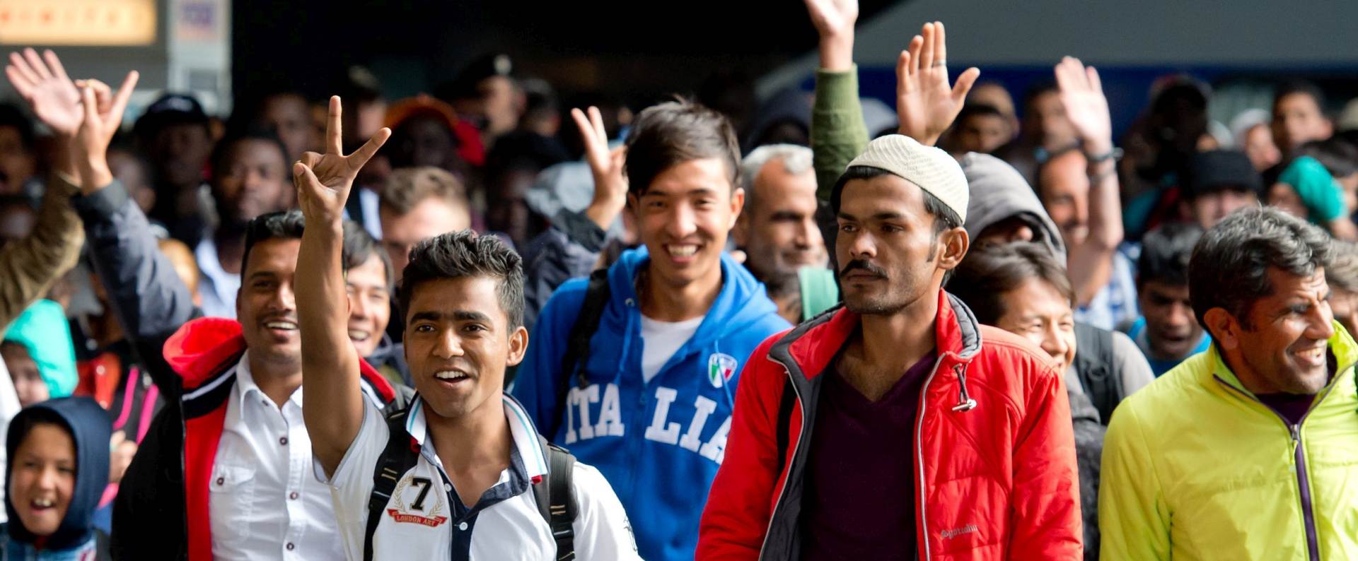 epaselect epa04917129 Refugees cheer as they arrive at the main train station in Munich, Germany, 06 September 2015. Thousands more exhausted refugees were setting foot in Germany for the second day 06 September after enduring grueling journeys across Hungary and Austria. Many of the refugees are fleeing war-torn countries such as Syria and Afghanistan, and thus qualify for international protection, but EU countries disagree on how to best handle the surge.  EPA/SVEN HOPPE