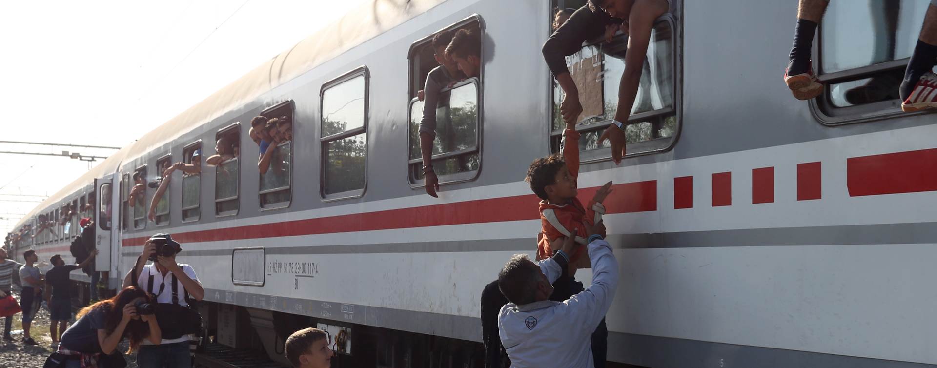 Tovarnik, 18.09.2015 - Izbjeglice se penju kroz prozore vlaka koji na eljeznièkoj stanici u Tovarniku stoji od sinoæ. Vlak iz Tovarnika prema Zagrebu je krenuo u 10.00 sati uz odobravanje izbjeglica u vlaku.
foto HINA/ Damir SENÈAR /ds