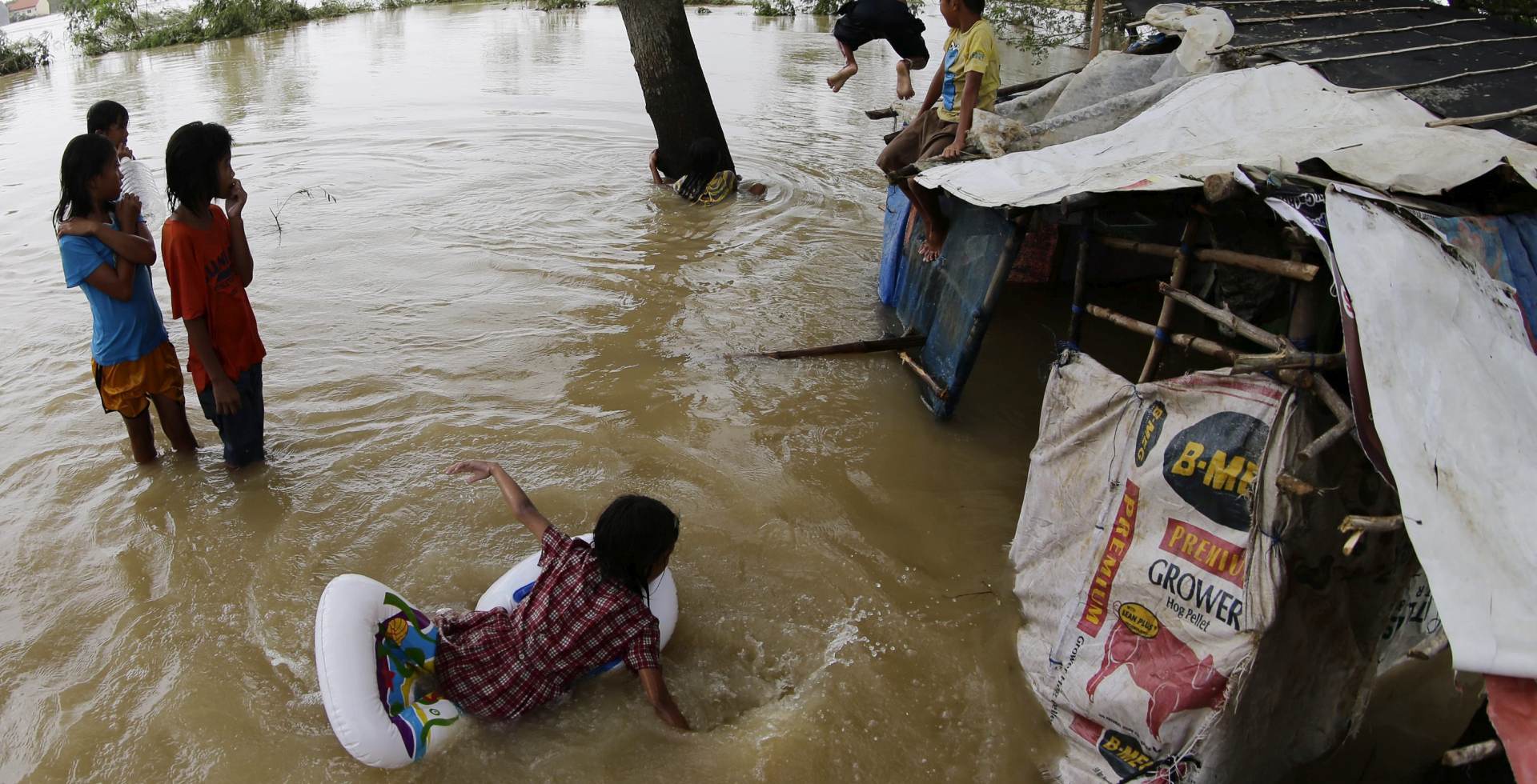 epa04984687 Although victims of the recent typhhon, Filipino children frolic next to a flooded shelter at the flood hit village of Santa Rosa, Nueva Ecija province, northern Philippines, 20 October 2015. Philippine emergency teams were attempting to reach victims stranded by flooding from Typhoon Koppu, and began clearing areas damaged by the storm which battered the north of the country. Soldiers, police officers and other emergency workers were dispatched to the northern province of Nueva Ecija, a rice-growing province where murky floodwaters reached up to rooftops in some places.  EPA/FRANCIS R. MALASIG