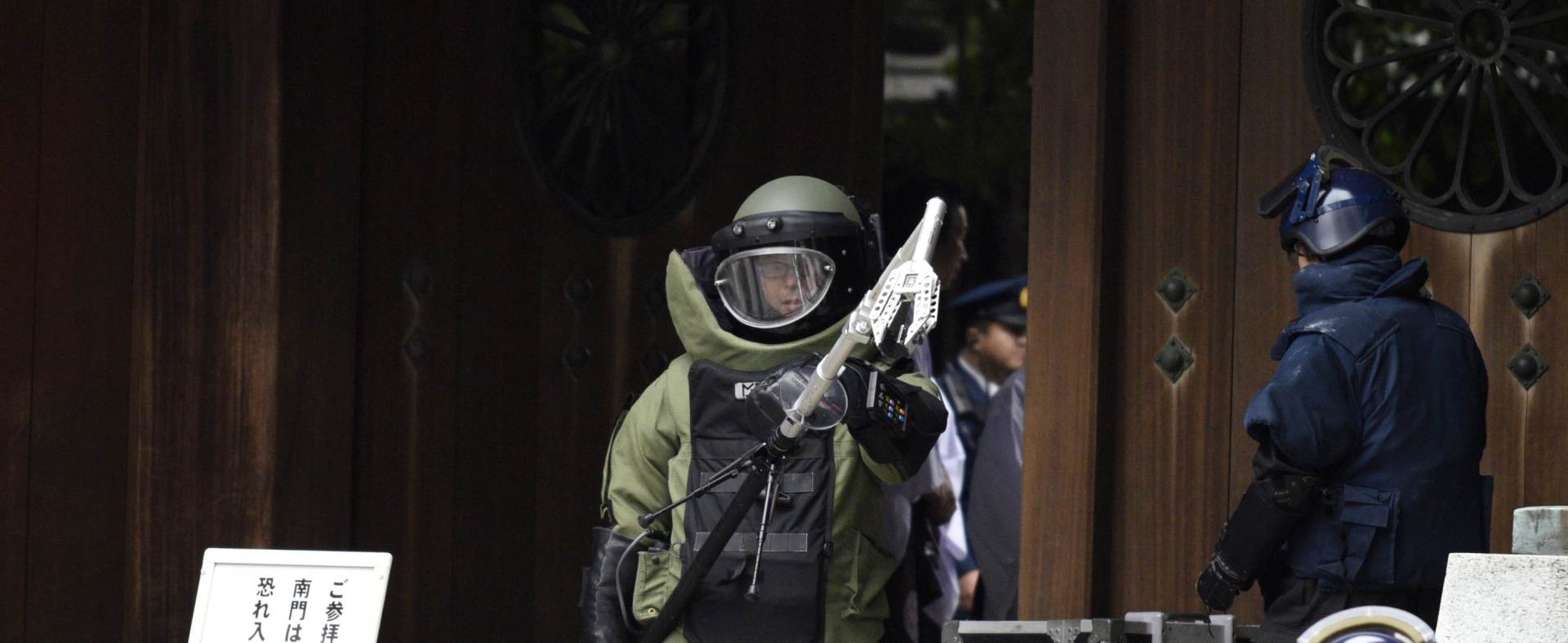 epa05038093 A bomb squad member wearing heavy equipment leaves the explosion site at the Yasukuni shrine precints in Tokyo, Japan, 23 November 2015. More than 100 police, firefighters and officials gathered at the site after an explosion was heard in the toilets of the Yasukuni Shrine, a controversial war shrine in the capital Tokyo. Local media reports said police found possible traces of an explosion, as well as batteries and wires at the shrine. There were no reports of injuries.  EPA/FRANCK ROBICHON