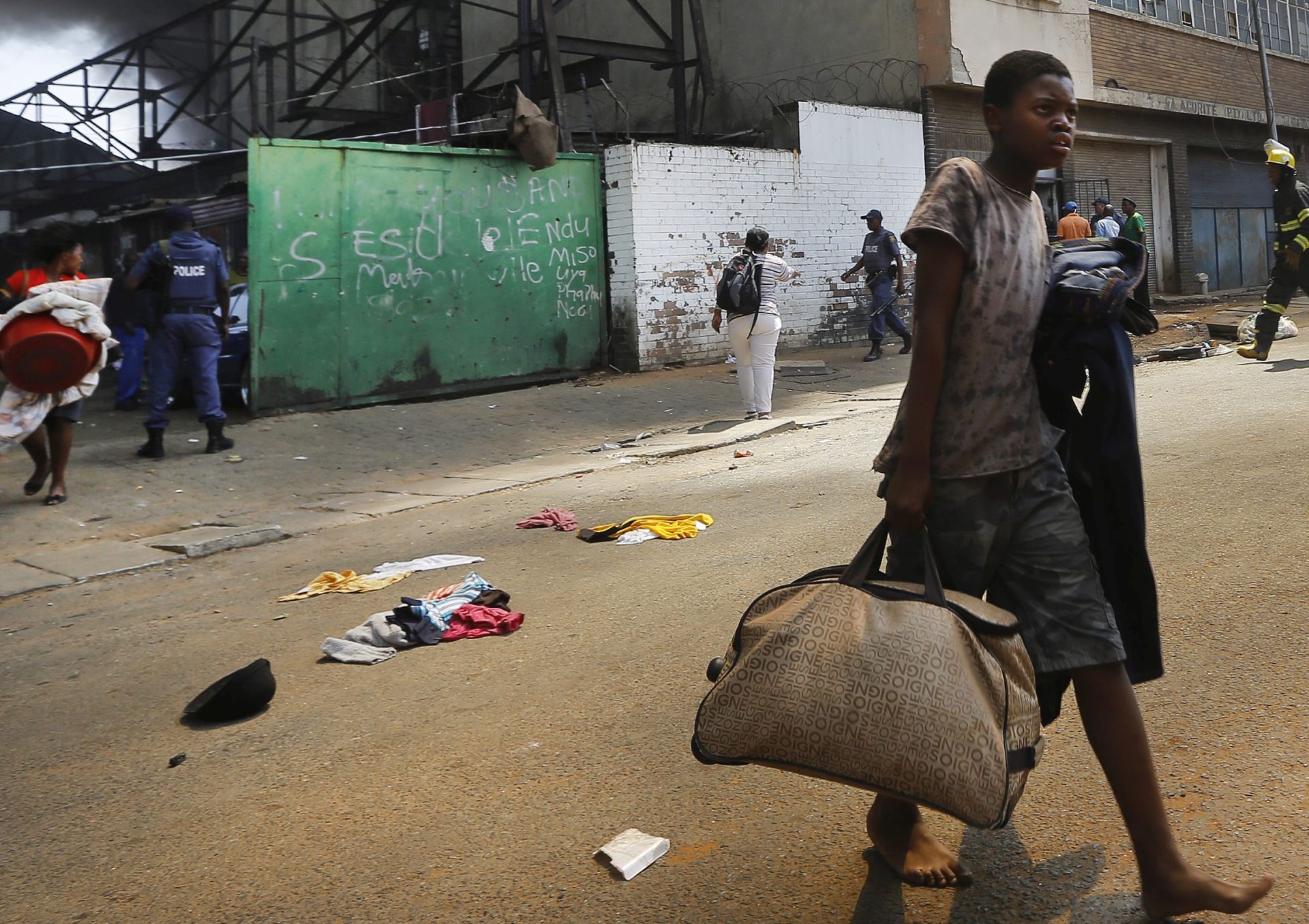 epa04996675 (01/22) A young boy carries all he can as he and other illegal residents of a hijacked building are evicted by South African police forces and a private security company in downtown Johannesburg, South Africa, 29 September 2015. It is unknown where he slept that night. The building, a warehouse, was set alight by some of the illegal residents that had been evicted. Hundreds of people had made the 'dark building' home after it was occupied years previously. It is unclear who the original owner is. Hundreds of people evicted had no other accommodation to go to and ended up sleeping on the streets as homeless.  EPA/KIM LUDBROOK PLEASE REFER TO THIS ADVISORY NOTICE (epa04996673) FOR FULL PACKAGE TEXT