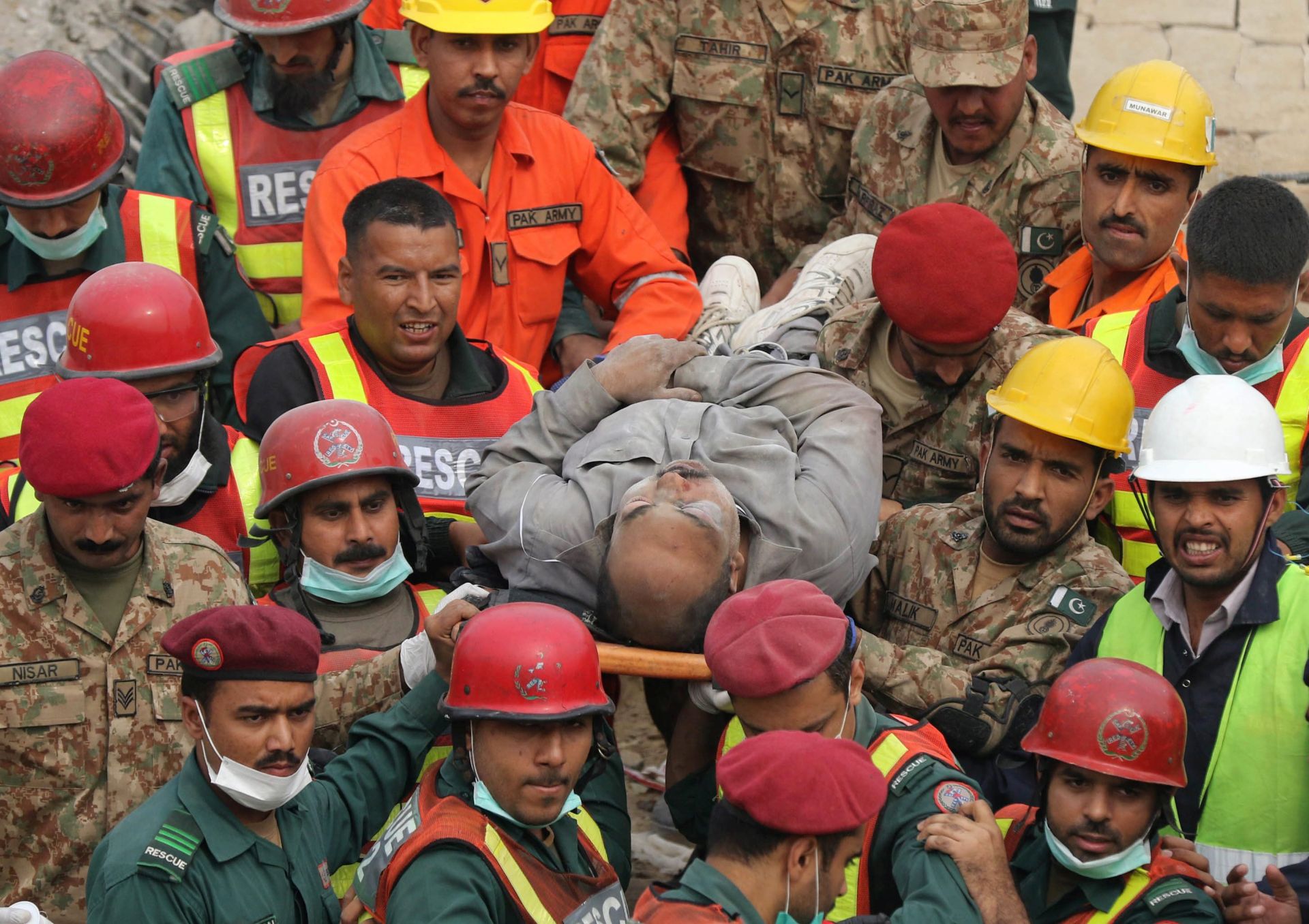 epa05011730 Rescue workers recover a body amid rubble of a factory that collapsed in Lahore, Pakistan, 05 November 2015. The roof of a multi-storey factory collapsed in Pakistan on 04 November, killing at least 19 workers and leaving about 150 trapped under the rubble, officials said. Rescuers were cutting through steel bars to look for survivors in an industrial district of the eastern city of Lahore, police official Haider Ashraf said.  EPA/RAHAT DAR