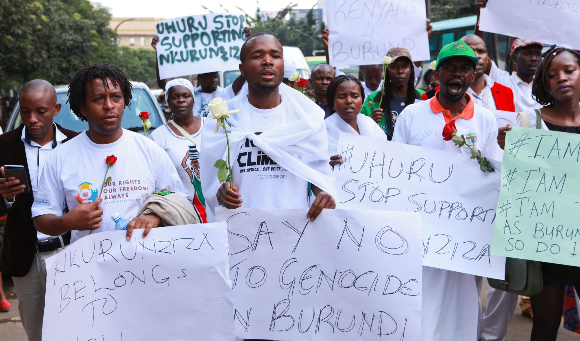 epa05074202 Kenyan activists and Burundians hold flowers and placards during a protest against killings in Burundi, in Nairobi, Kenya, 18 December 2015. Kenyans and Burundian nationals marched to the Burundian Embassy to Kenya to condemn the violence between police and opposition groups since April, when President Pierre Nkurunziza announced he would seek a third term in office. Human rights activists say more than 240 people have been killed in protests and attacks since April, while more than 220,000 are believed to have fled the country. The African Union said on 17 December 2015, it would not allow genocide to take place in Burundi.  EPA/DANIEL IRUNGU