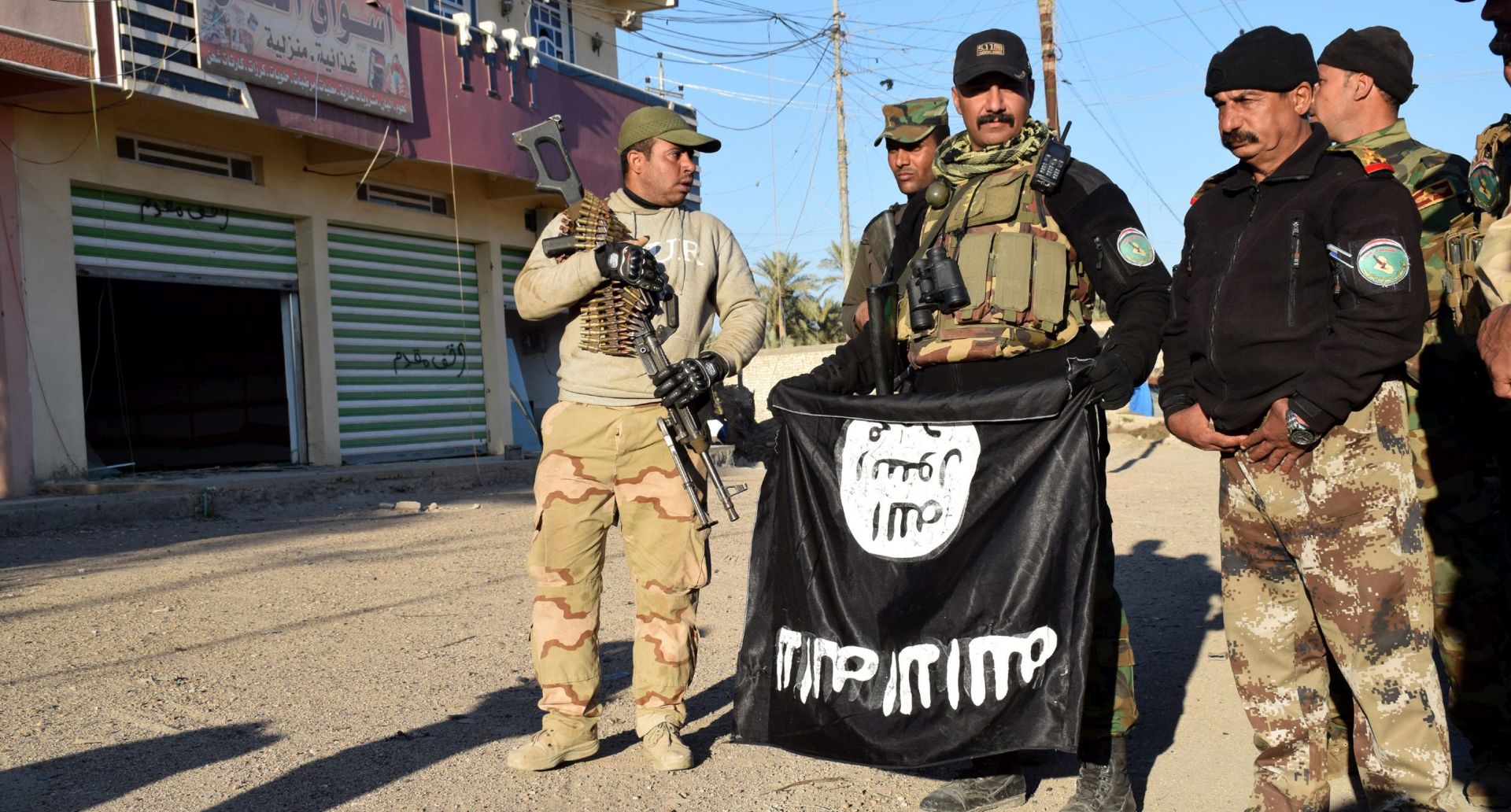 epa05106689 A photograph made available on 17 January 2016 shows Iraqi soldiers holding a flag of the Islamic State group after they gained control of the Ramadi city, western Iraq, 16 January 2016. Iraqi government last month announced the "liberation" of the western city of Ramadi from Islamic State, marking the first major setback for the radical Sunni group since April. Since Ramadi's recapture, IS has carried out a series of attacks in several parts of Iraq where it still controls large swathes of territory.  EPA/NAWRAS AAMER
