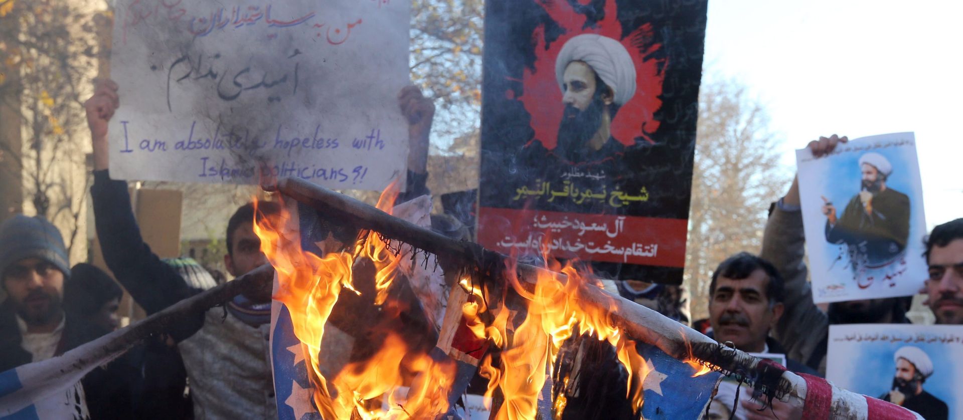 epa05086825 Iranian protestors burn US and Israeli flags as they hold posters of late Shiite cleric Nimr al-Nimr during a demonstration near the Saudi Arabian embassy in Tehran, Iran, 03 January 2016. Iranian Protesters have stormed the Saudi embassy building in the Iranian capital of Tehran early 03 January amid backlash over the execution of a prominent Shiite cleric. Flammable substance was seen thrown at the building as protests gained steam over the execution of Sheikh Nimr al-Nimr. Reports states, protesters taking down a Saudi flag and burned the building.  EPA/ABEDIN TAHERKENAREH