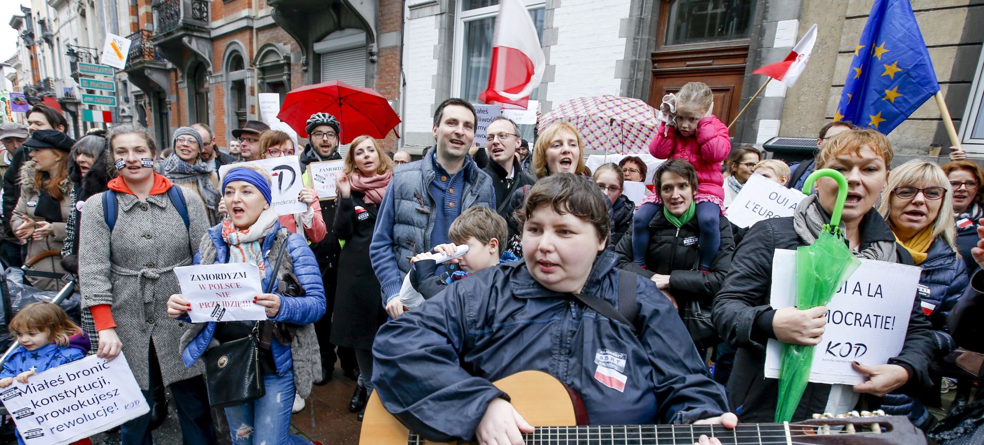 epa05075160 Polish supporters of the Committee for the defense of democracy take part a stand up demonstration in front of the Polish embassy in Brussels, Belgium, 19 December 2015, The campaign against Polish government and President is part of a World day of protest to call for a return of democracy in Poland. Earlier this week European Parliament  President, German, Martin Schulz said that the newly elected Polish government's assumption of power resembles a coup.  EPA/OLIVIER HOSLET