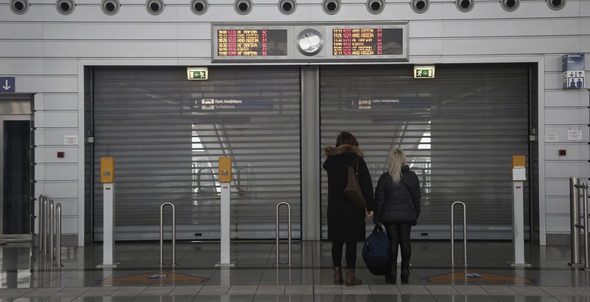 epa05142365 Women stand in front of a closed suburban station at the Athens Eleftherios Venizelos airport during a 24-hour national strike, in Athens Greece, 04 February 2016. Greece's  largest private and public sector unions GSEE and ADEDY held a strike on 04 February to protest against the government's planned pension reforms. Public transport was grinding to a halt, while trains were cancelled and ferries stayed put in harbours, also cutting off the Greek islands from the mainland.  EPA/YANNIS KOLESIDIS