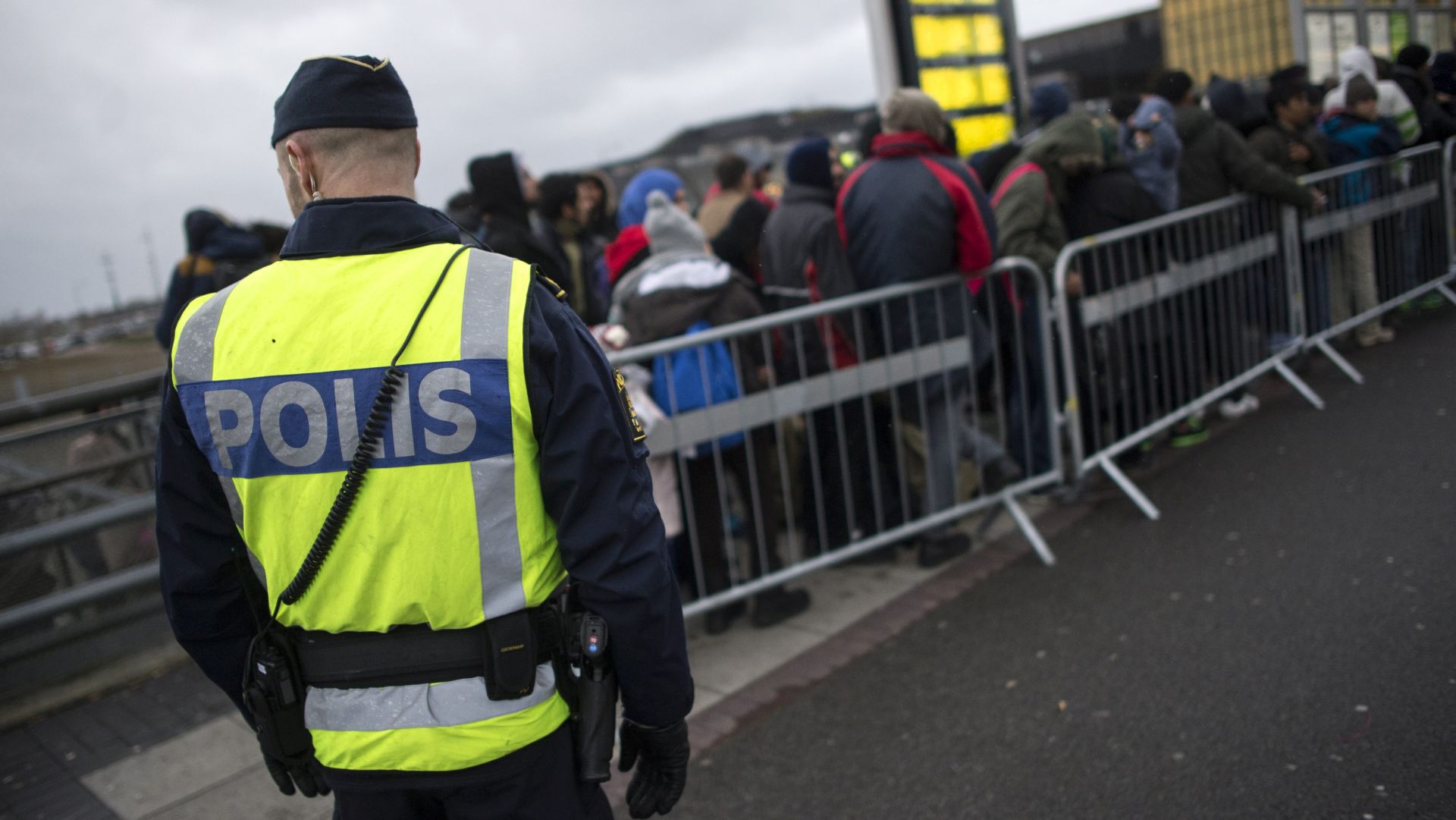 epa05131191 A picture made available 28 January 2016 shows a Swedish policeman watching newly arrived refugees at Hyllie station outside Malmoe, Sweden, 19 November 2015. Sweden is preparing for the expulsion of up to 80,000 people whose asylum bids have been rejected, a cabinet member said 28 January 2016. A record 163,000 people applied for asylum in Sweden in 2015, straining resources and capacity at reception centres and local municipalities. The increase of explusions will be likely only at the beginning of 2017 though, due to the backlog the Swedish Migration Agency was struggeling with.  EPA/JOHAN NILSSON SWEDEN OUT