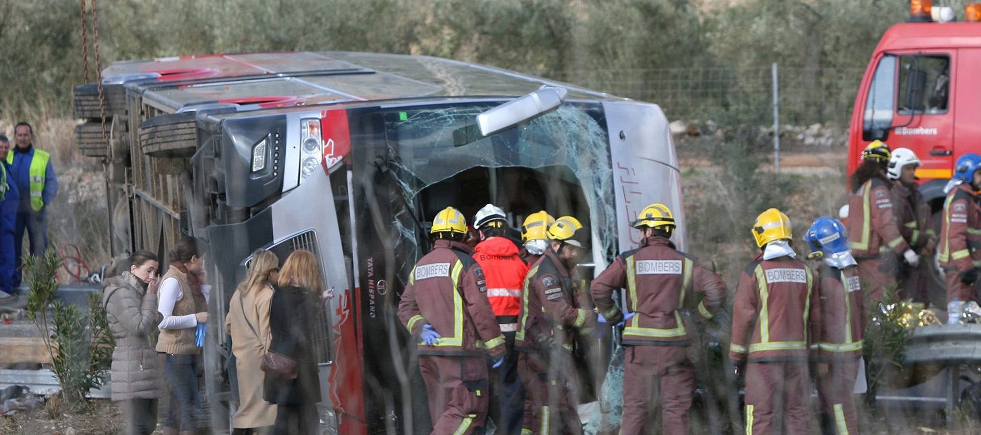 epa05222062 Firemen work at the site of a coach crash that has left at least 14 students dead at the AP-7 motorway in Freginals, in the province of Tarragona, northeastern Spain, 20 March 2016. The coach carrying dozens of Erasmus students collided with a car and overturned. The students from several different countries were heading to Barcelona after attending Las Fallas Festival in Valencia, eastern Spain.  EPA/JAUME SELLART