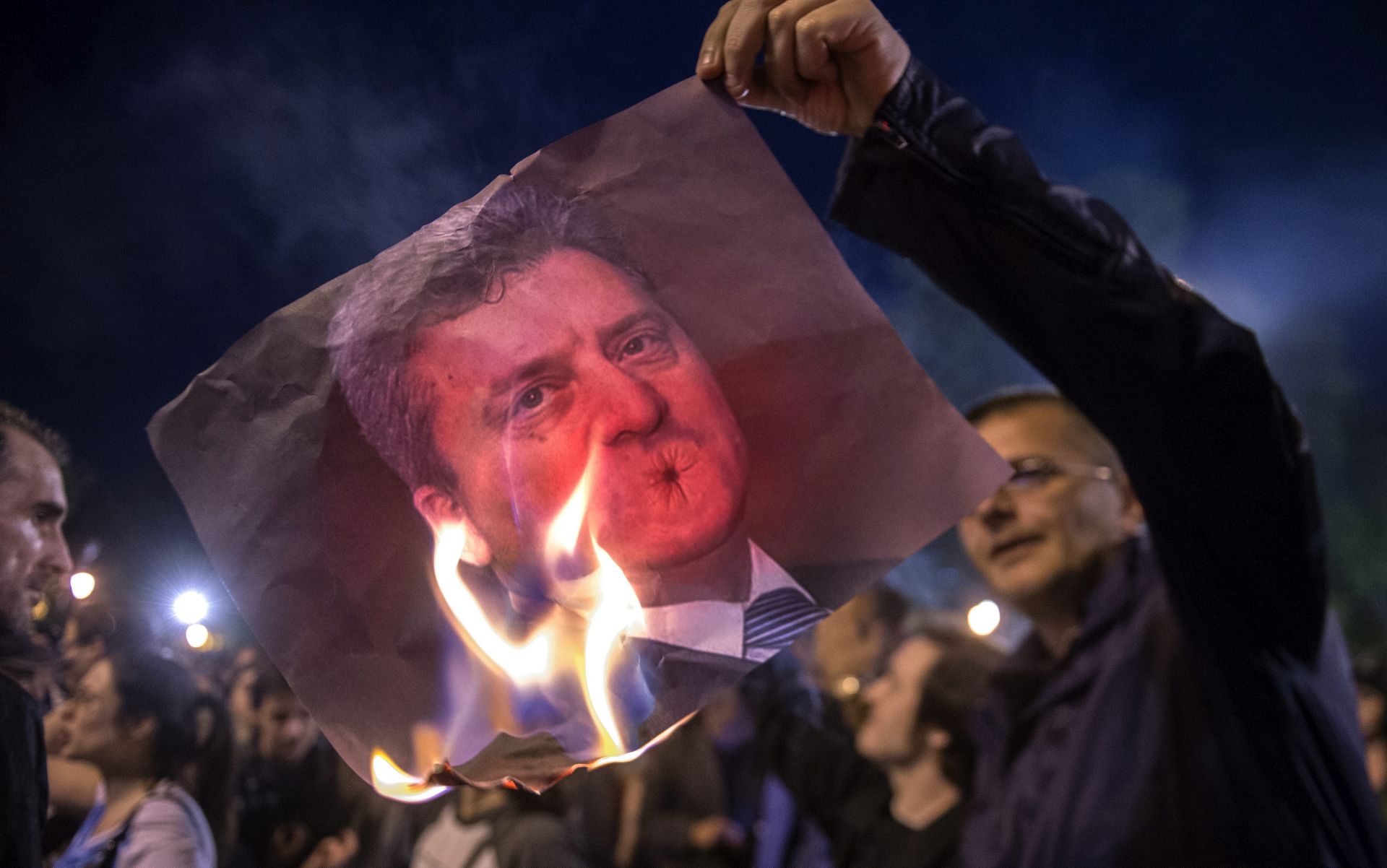 epa05257654 Protesters burn the picture of Macedonian President George Ivanov during the protest against Macedonian President Gjorge Ivanov's decision on wiretapping amnesty, in Skopje, Macedonia, 13 April 2016. Ivanov decided to abolish all judicial cases related to the big wire-tapping scandal that brought the country to early general elections scheduled for 05 June. The crisis started in 2015 when opposition SDSM started to publish illegally recorded wire-tapped phone conversations of the highest Governmental officials claiming they show financial crime and eventual evidences of electoral frauds of the ruling conservative VMRO-DPMNE party of then PM Gruevski. Gruevski denied everything saying 'foreign intelligence services' are trying to topple his Government he was administrating from 2006.  EPA/NAKE BATEV