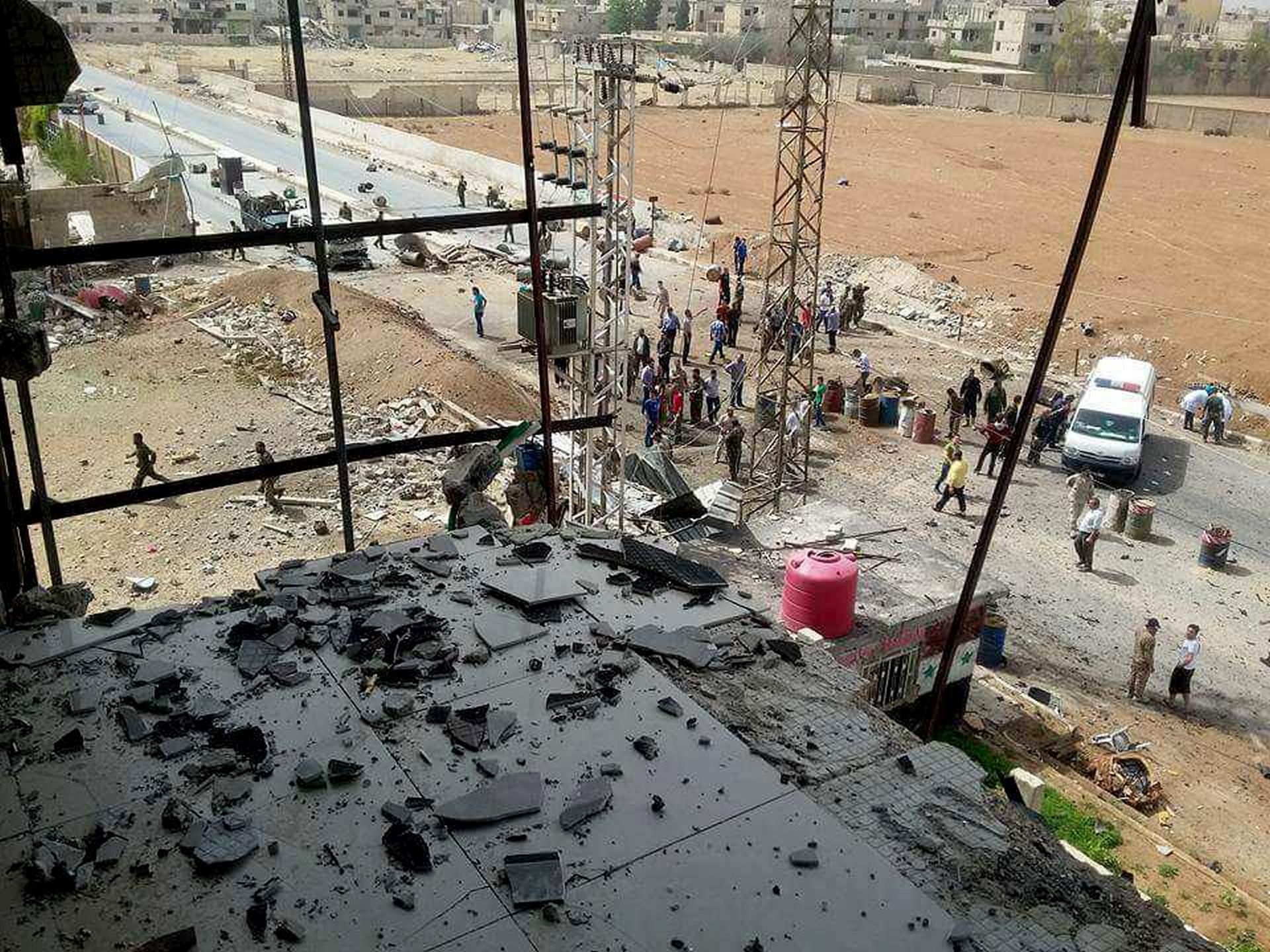 epa05276651 A handout picture made available by Syrian Arab News Agency (SANA) shows Syrian policemen inspecting the site of bombing, at the entrance of al-Diabiyeh town in Damascus countryside , Syria, 25 April 2016. According to SANA, five civilians were killed and 20 others were injured in the car bombing.
