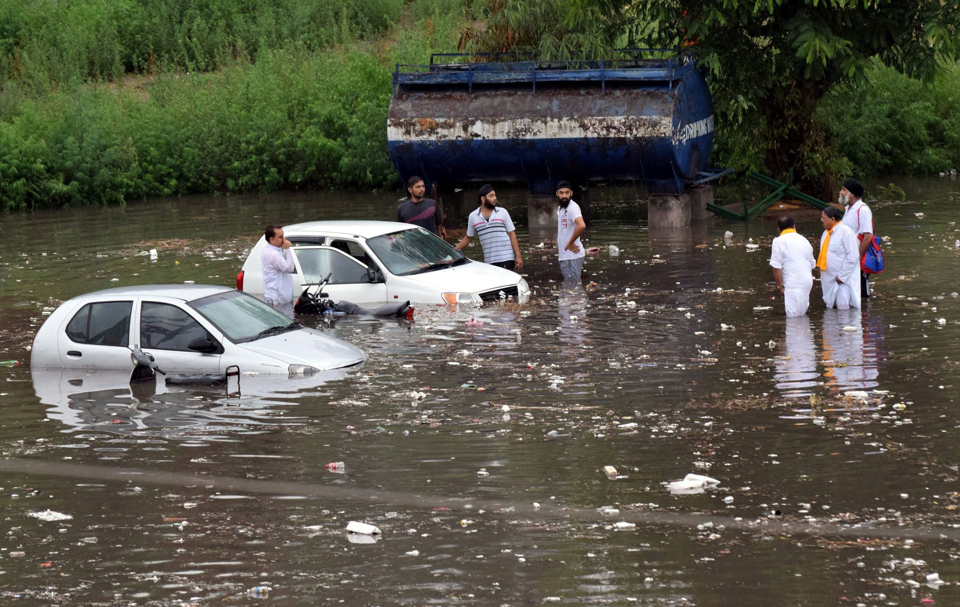 epa05380815 Indian people stands with their drowned vehicles at parking of Maulana Azad Stadium after a heavy monsoon shower in Jammu, the winter capital of Kashmir, India, 21 June 2016. Rain water flooded the entire Jammu city, paralyzing the traffic.  EPA/JAIPAL SINGH
