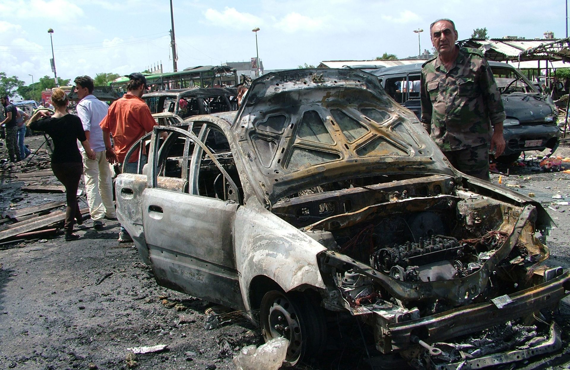 epa05324988 A handout photograph released by the official Syrian Arab News Agency (SANA) shows an officer standing next to damaged cars at the site of car bombing in a bus station in the Jableh city, Lattakia province, Syria, 23 May 2016. According to SANA, at least 78 people were killed and scores injured in a series of bombings in the coastal cities of Tartous and Jableh.  EPA/SANA HANDOUT  HANDOUT EDITORIAL USE ONLY/NO SALES