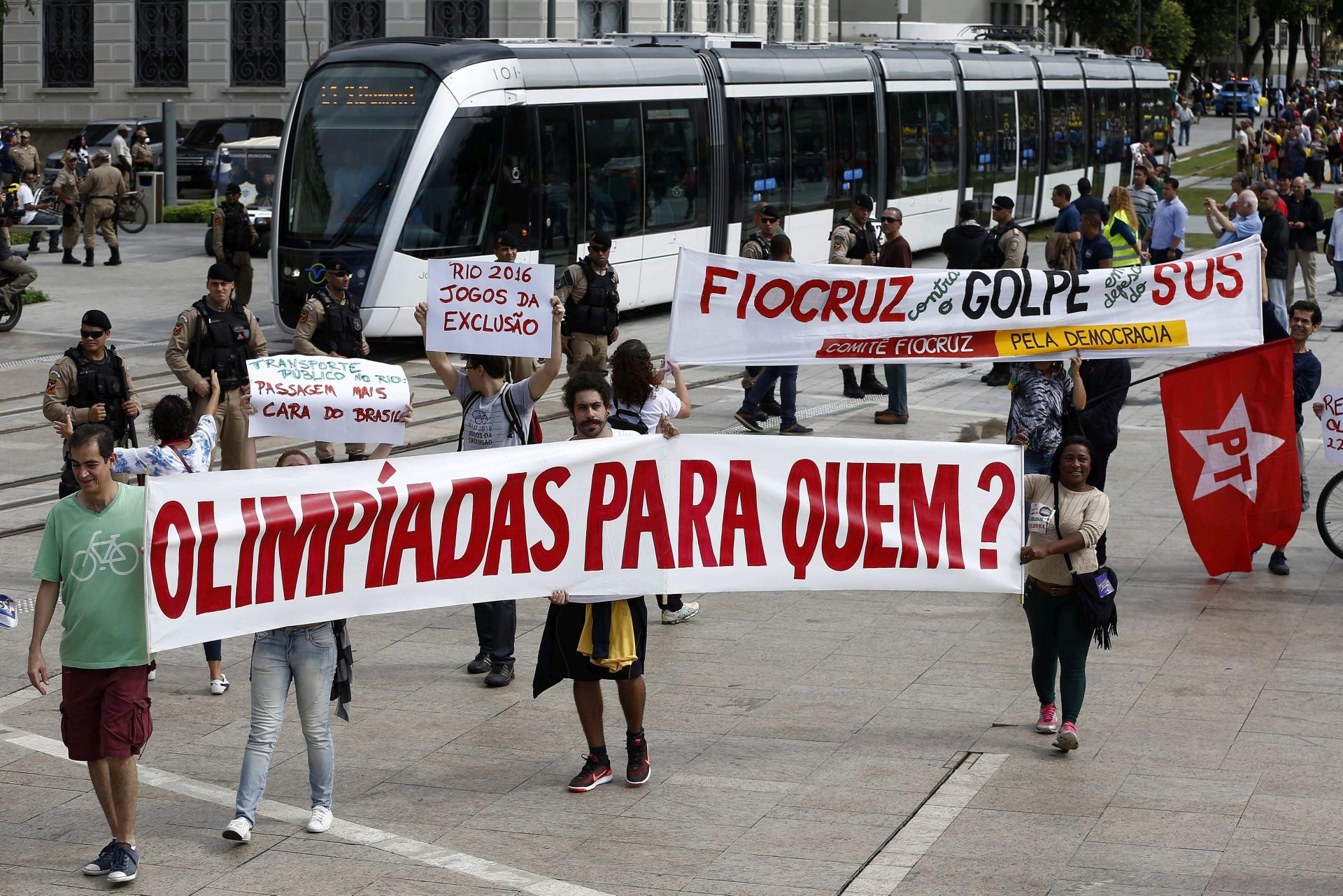 epa05347628 A group of people protesting with banners that read 'Olympics for whom' as an electric tramway that will travel through several streets of the city center replacing numerous bus lines and was conceived as one of the main Olympic legacies begins operating in Rio de Janeiro, Brazil, on 05 June 2016.  EPA/Marcelo Sayao