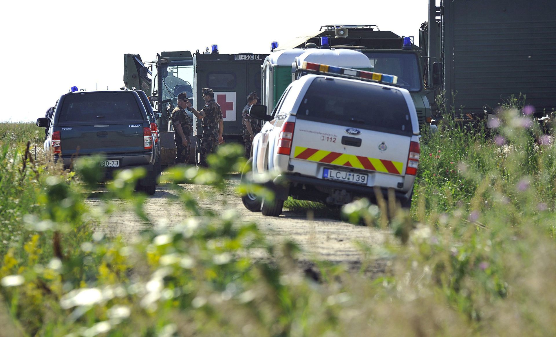 epa05401797 A military ambulance vehicle (C) stands by a road leading to a former shooting range on the territory of the Hortobagy National Park, near Nadudvar, 193 kilometers east of Budapest, Hungary, 01 July 2016, after four bomb disposal experts of the Hungarian army were killed when a WWII bomb unexpectedly exploded while experts tried to defuse it.  EPA/ZSOLT CZEGLEDI HUNGARY OUT