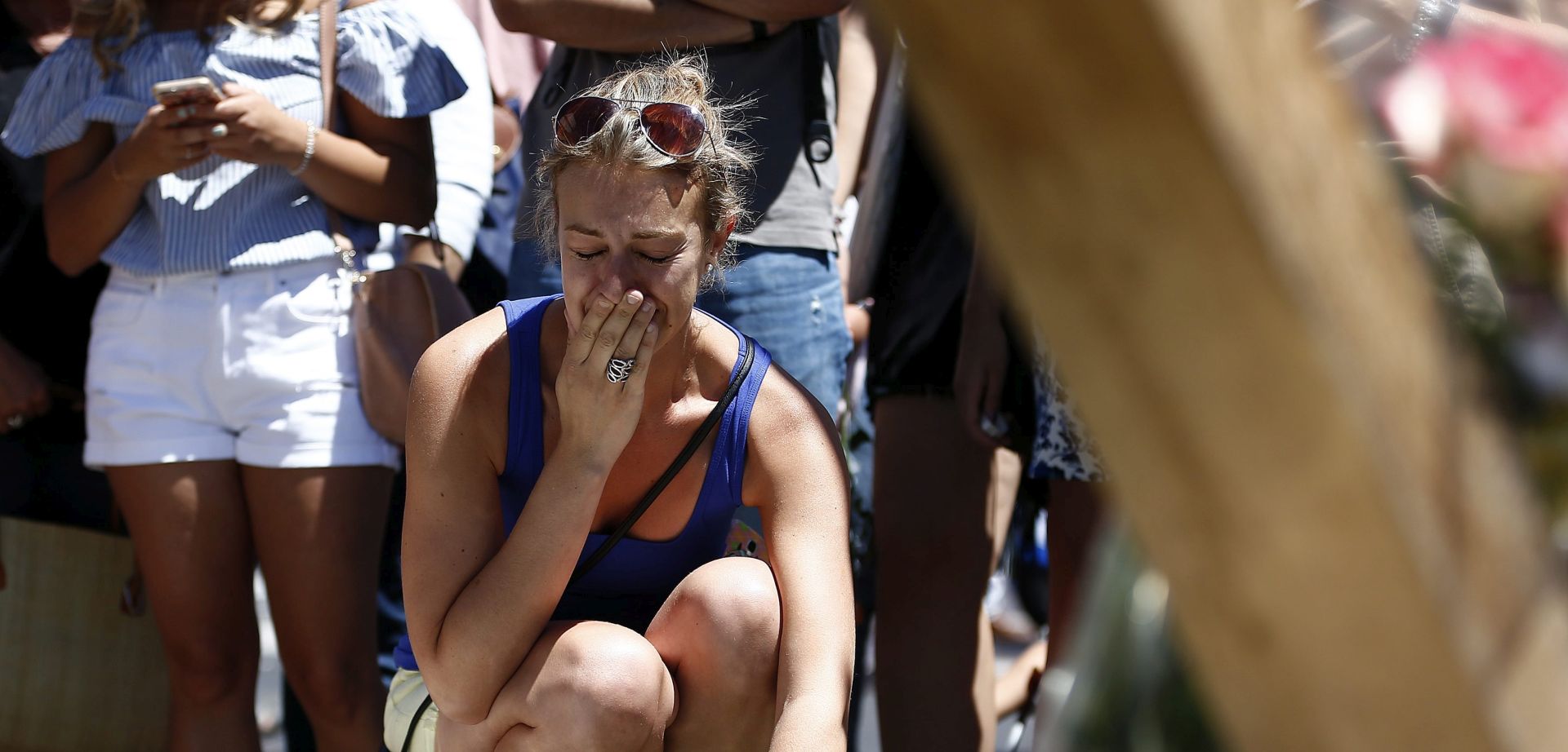 epa05426134 A woman reacts as she places flowers in front of the memorial set on the 'Promenade des Anglais' where the truck crashed into the crowd during the Bastille Day celebrations in Nice, France, 15 July 2016. According to reports, at least 84 people died and many were wounded after a truck drove into the crowd on the famous Promenade des Anglais during celebrations of Bastille Day in Nice, late 14 July. Anti-terrorism police took over the investigation in the incident, media added.  EPA/IAN LANGSDON