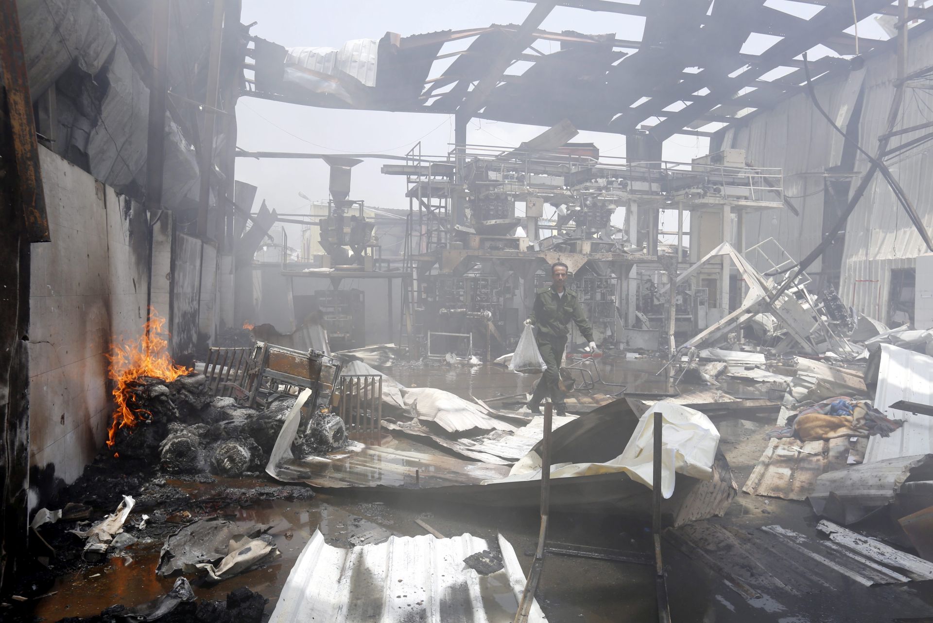 epa05467107 A Yemeni soldier inspects a food factory allegedly targeted by a Saudi-led airstrike in Sana'a, Yemen, 09 August 2016. According to reports, the Saudi-led military coalition conducted airstrikes on the capital Sana'a, including a food factory, killing at least 14 workers and wounding dozens others, few days after UN-sponsored peace talks in Kuwait between Yemen's warring factions were halted.  EPA/YAHYA ARHAB