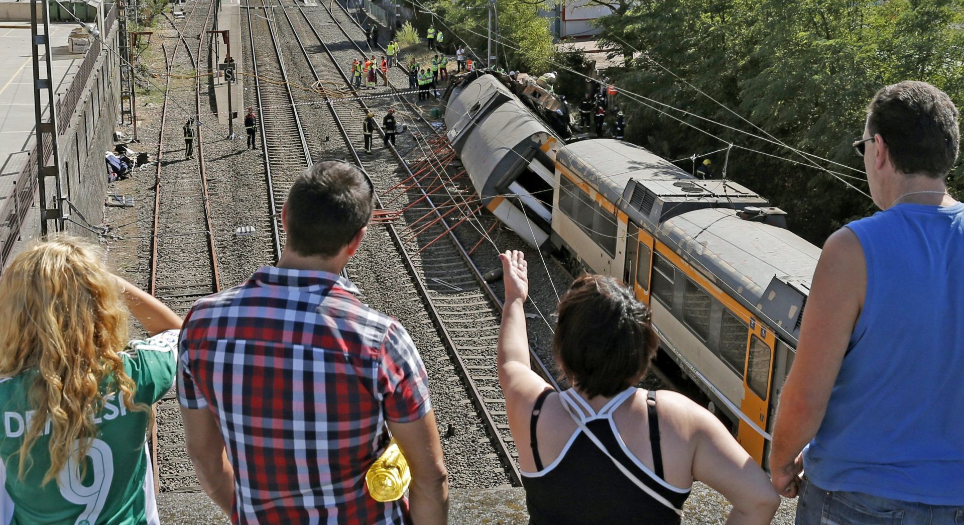 epa05532103 People watch emergency services personell work at the site of a train derailment near O Porrino in Pontevedra, resulting in the death of at least four people and the injury of another 50 people, in the northwestern province of Galicia, Spain, 09 September 2016. The train covering the Vigo-Oporto (Portugal) route was carrying some 60 passengers when one of its three coaches overturned provoking the accident. Spanish rail service Renfe has confirmed that at least two people were dead and a large number injured, some of them serious. Renfe also said that the train belongs to Portuguese company Comboios and that the engine driver has Portuguese citizenship.  EPA/SALVADOR SAS