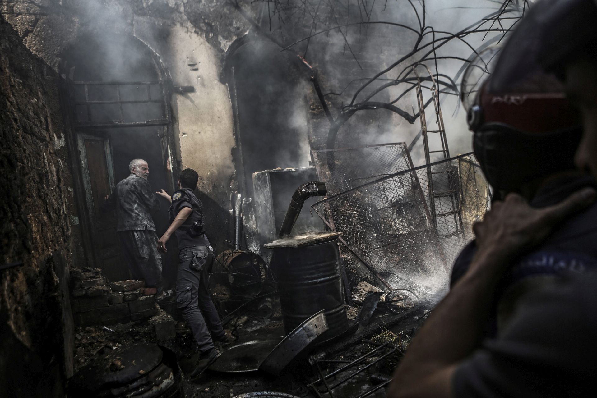epa05671682 (FILE) A file picture dated 11 September 2016 shows White Helmets volunteer Hassan al-Muhshi (C) speaking to a man as firefighters extinguish a fire following an airstrike by forces loyal to the Syrian government in the rebel-held area of Douma, outskirts of Damascus, Syria. According to local sources, at least five people were killed in shelling and bombing on 11 December allegedly carried out by forces loyal to Syrian goverment, among them White Helmets volunteer Hassan al-Muhshi.  EPA/MOHAMMED BADRA