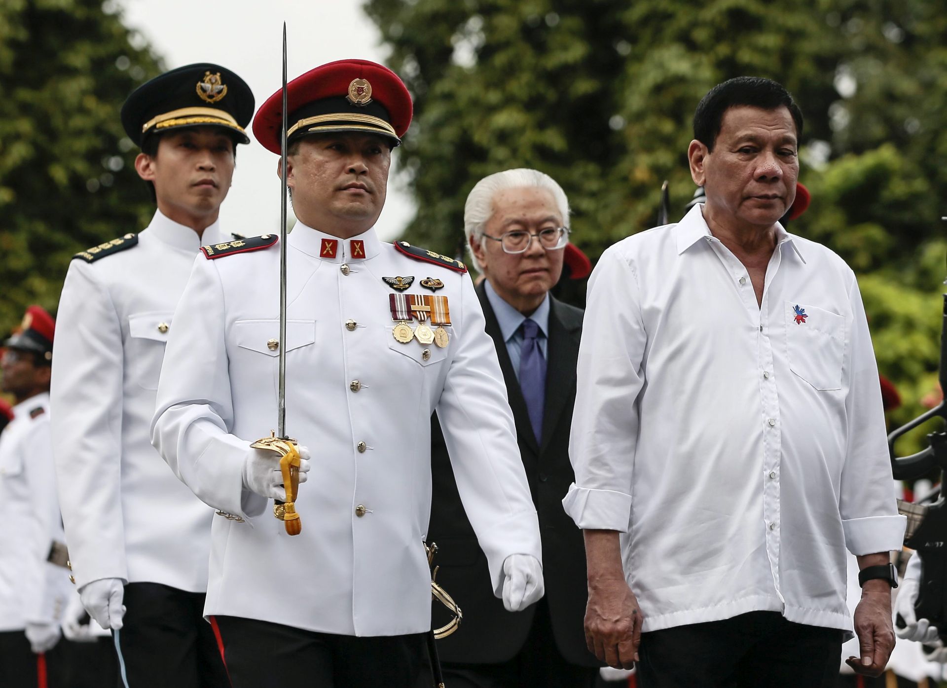 epa05676308 Filipino President Rodrigo Duterte (R) and Singapore President Tony Tan Keng Yam (C-R) inspect the honor guard during a welcome ceremony at the Istana Presidential Palace in Singapore, 15 December 2016. Duterte is on his first state visit to Singapore and will meet with members of the Filipino community.  EPA/WALLACE WOON