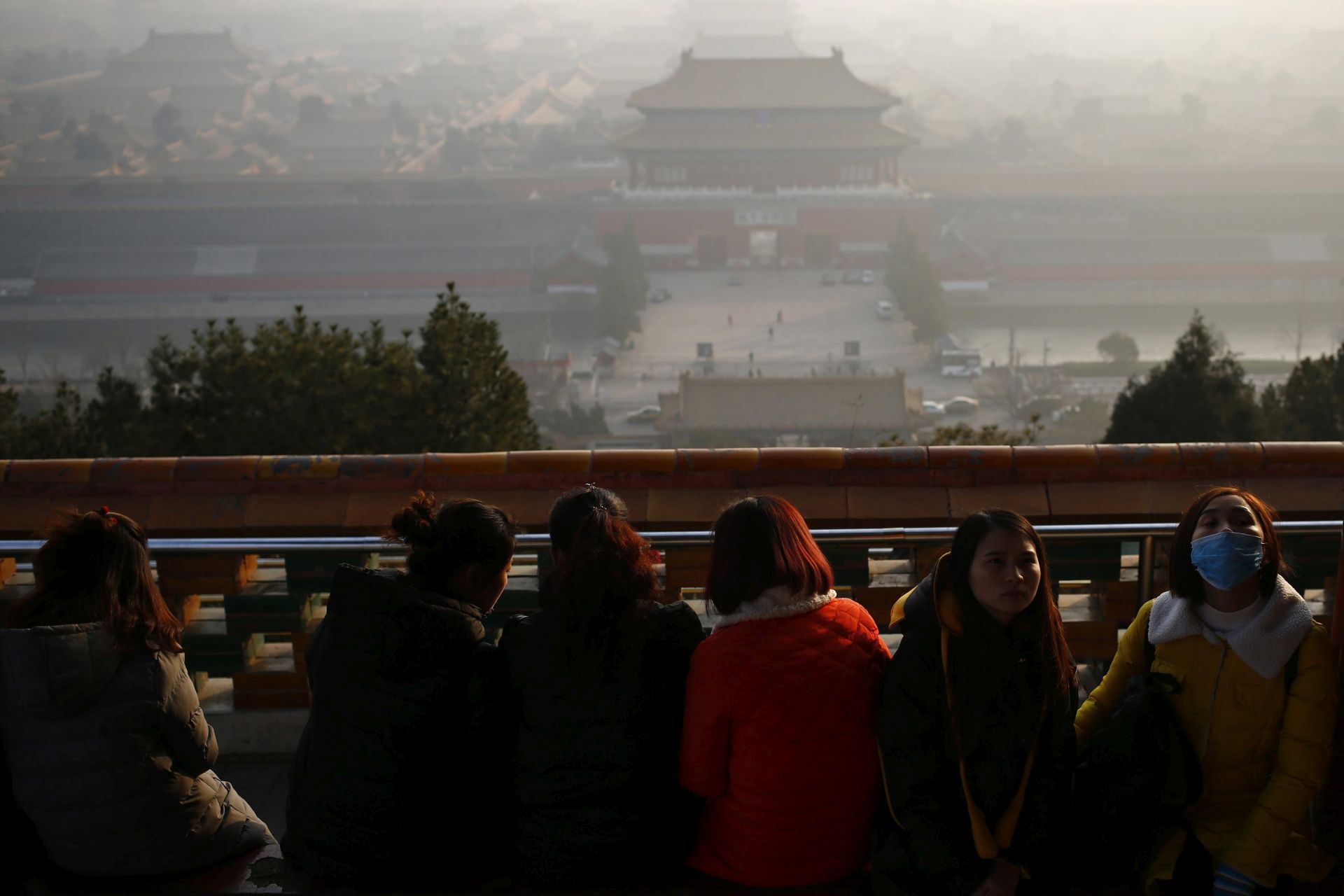 epa05682031 A woman wears mask at Jingshan Park while haze hangs over the Forbidden City in Beijing, China, 19 December 2016. Serious air pollution hit in China's nine provinces and cities, with haze hanging over an area of about 1.42 million square kilometers on 18 December. The air pollution alert lasts in many part of China that the heavy pollution is expected to persist over 11 provinces and cities on 19 December 2016.  EPA/WU HONG