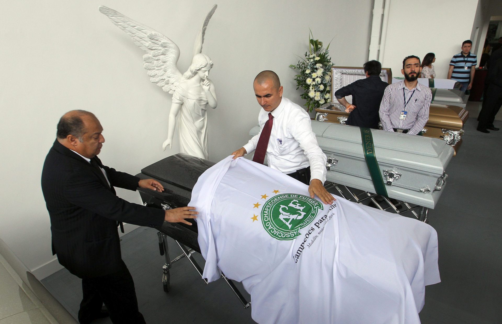 epa05655573 Workers place the Chapecoense soccer team flags at San Vicente funeral home on some of the victims of the LaMia Bolivian airline accident, including the players of the Brazilian soccer team Chapecoense, in Medellin, Colombia, 01 December 2016. 71 people died when an aircraft crashed late 28 November 2016 with 77 people on board, including players and staff of the Brazilian soccer club Chapecoense. The plane crashed in a mountainous area outside Medellin, Colombia as it was approaching the Jose Maria Cordoba airport. Chapecoense were scheduled to play in the Copa Sudamericana final against Medellin's Atletico Nacional on 30 November 2016.  EPA/MAURICIO DUENAS CASTANEDA
