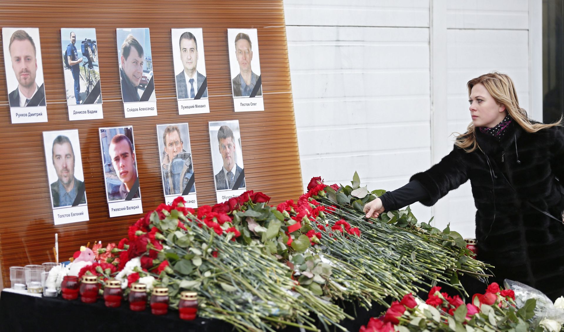 epa05688455 A woman places flowers before portraits of Russian TV journalists who were aboard the crashed Tu-154 Russian military plane, at a small memorial outside the Ostankino television center in Moscow, Russia, 26 December 2016. There were 92 persons on board the flight that crashed into the Black Sea near Sochi shortly after taking off, 25 December. Passengers included 65 members of Alexandrov Song and Dance ensemble, eight crew members, nine Russian journalists as well as Russian civil activist, Doctor Yelizaveta Glinka (Doctor Liza). No survivors have been found.  EPA/SERGEI ILNITSKY