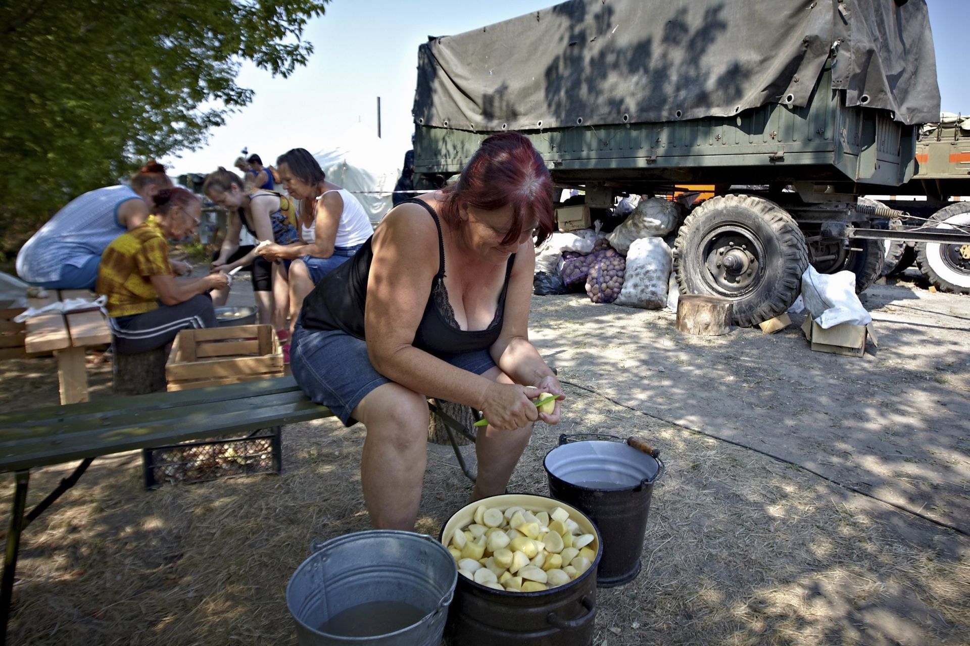 epa04351303 A picture made available on 13 August shows a Ukrainian woman from eastern Ukraine preparing food at a temporary refugee camp in Svatovo village, Lugansk area, Ukraine, 12 August 2014. A convoy of Russian aid trucks were heading to Ukraine's Luhansk region, where hundreds of thousands of civilians have been without electricity and mains water for 10 days. The convoy was due to reach embattled eastern Ukraine early 13 August, amid requests from Kiev that the 280 trucks be searched for military gear and threats to block the delivery.  EPA/SERGEI KOZLOV