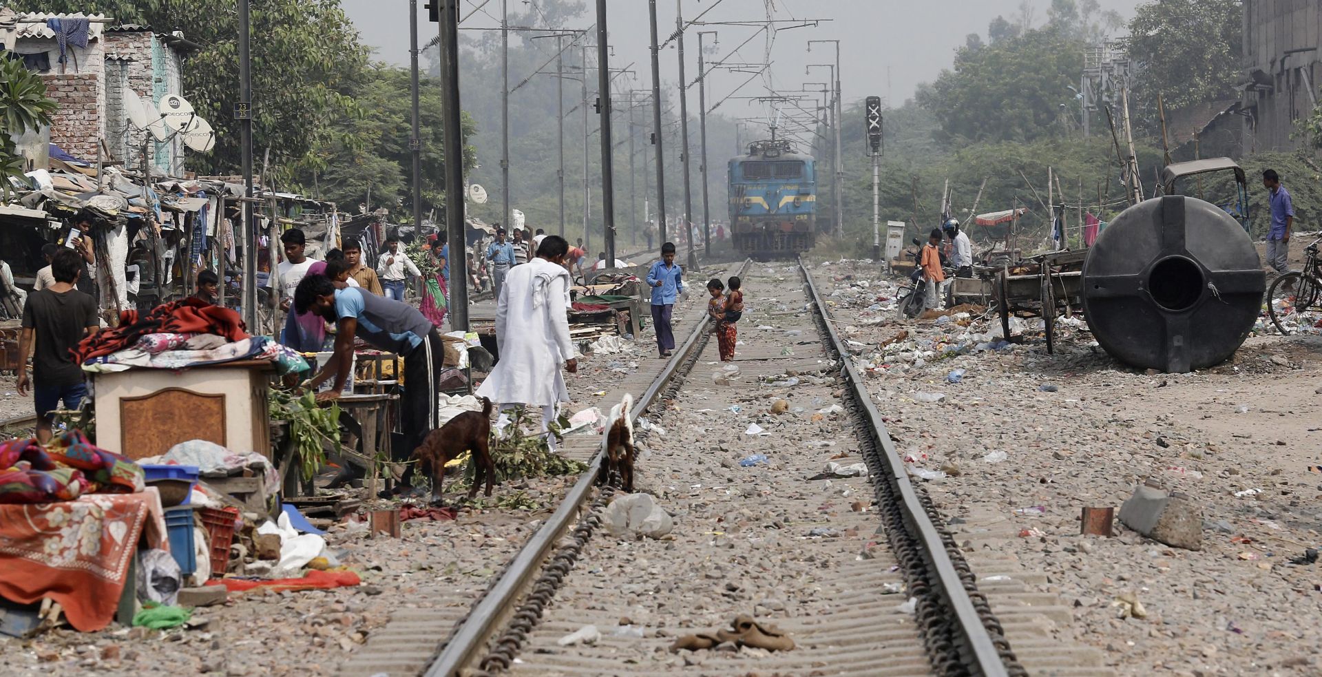 epa04976967 People stand near train tracks in a slum area where a four-year-old girl was allegedly raped, New Delhi, India, 14 October 2015. According to media reports, two men are being questioned by police related to the rape of a 4-year-old girl in Delhi. The girl was found by some railway lines on 09 October and is in hospital with serious injuries.  EPA/RAJAT GUPTA