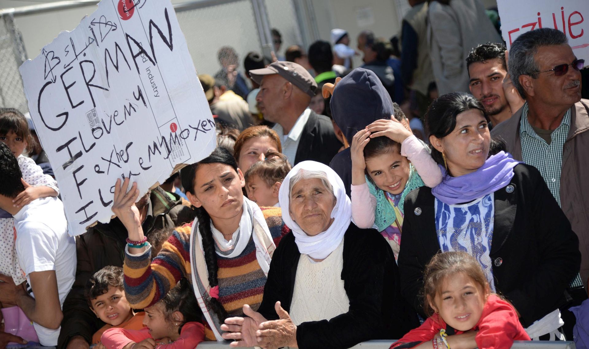 epa05261534 Migrants and refugees hold placards as Pope Francis visits the Moria refugee camp near the port of Mytilene on the island of Lesbos, Greece, 16 April 2016. Pope Francis visits the Greek island of Lesbos on 16 April, in a trip aimed at supporting refugees and drawing attention to the frontline of Europe's migration crisis.  EPA/FILIPPO MONTEFORTE / POOL