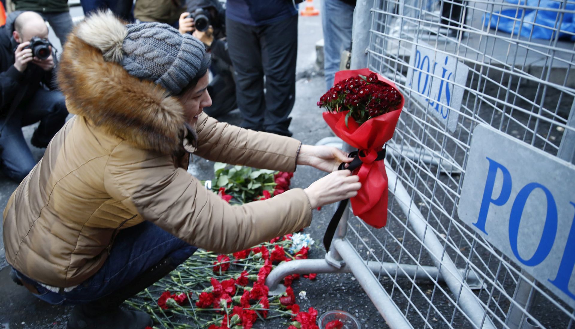 epa05694414 People place flowers and candles at a police barrier in front of the Reina night club following a gun attack at the popular night club in Istanbul close to the Bosphorus river, in Istanbul, Turkey, 01 January 2017. At least 39 people were killed and 65 others were wounded in the attack, local media reported.  EPA/DENIZ TOPRAK