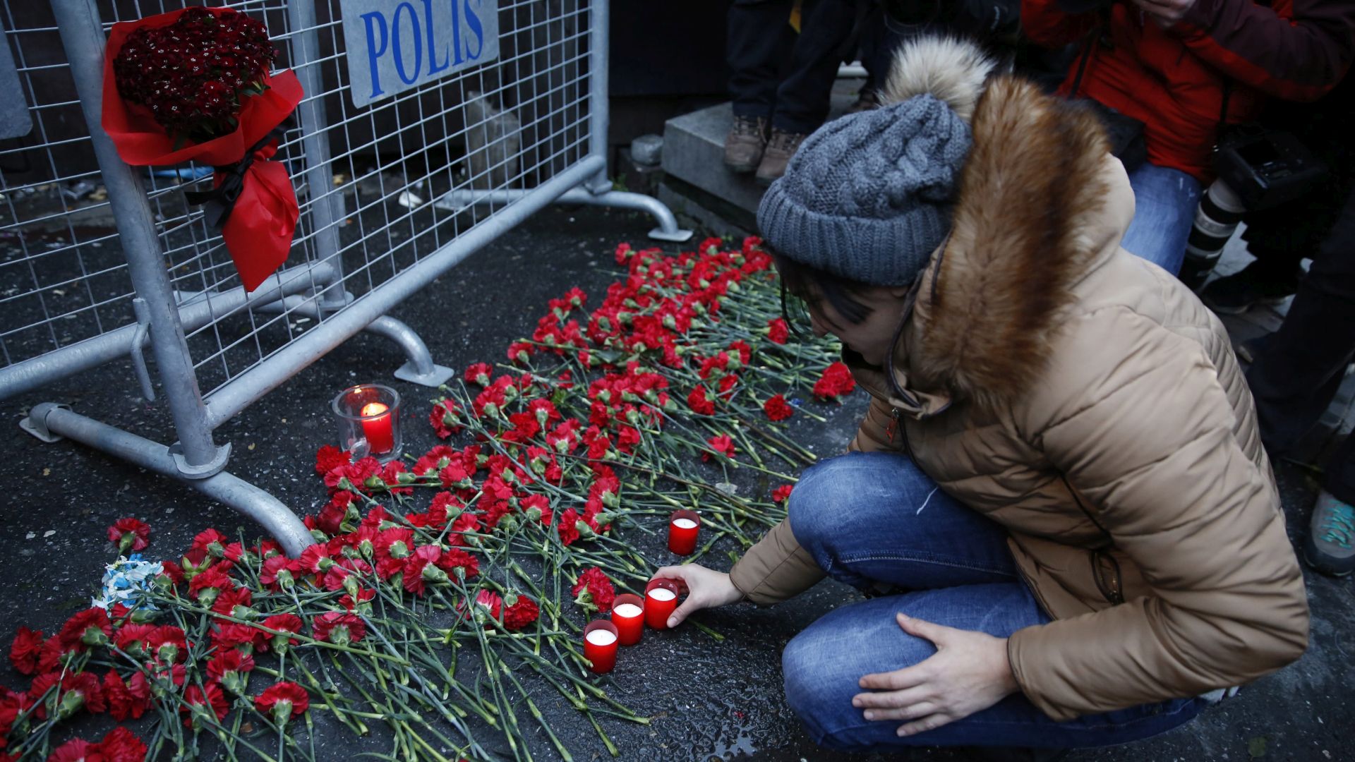 epa05694413 People place flowers and candles at a police barrier in front of the Reina night club following a gun attack at the popular night club in Istanbul close to the Bosphorus river, in Istanbul, Turkey, 01 January 2017. At least 39 people were killed and 65 others were wounded in the attack, local media reported.  EPA/DENIZ TOPRAK