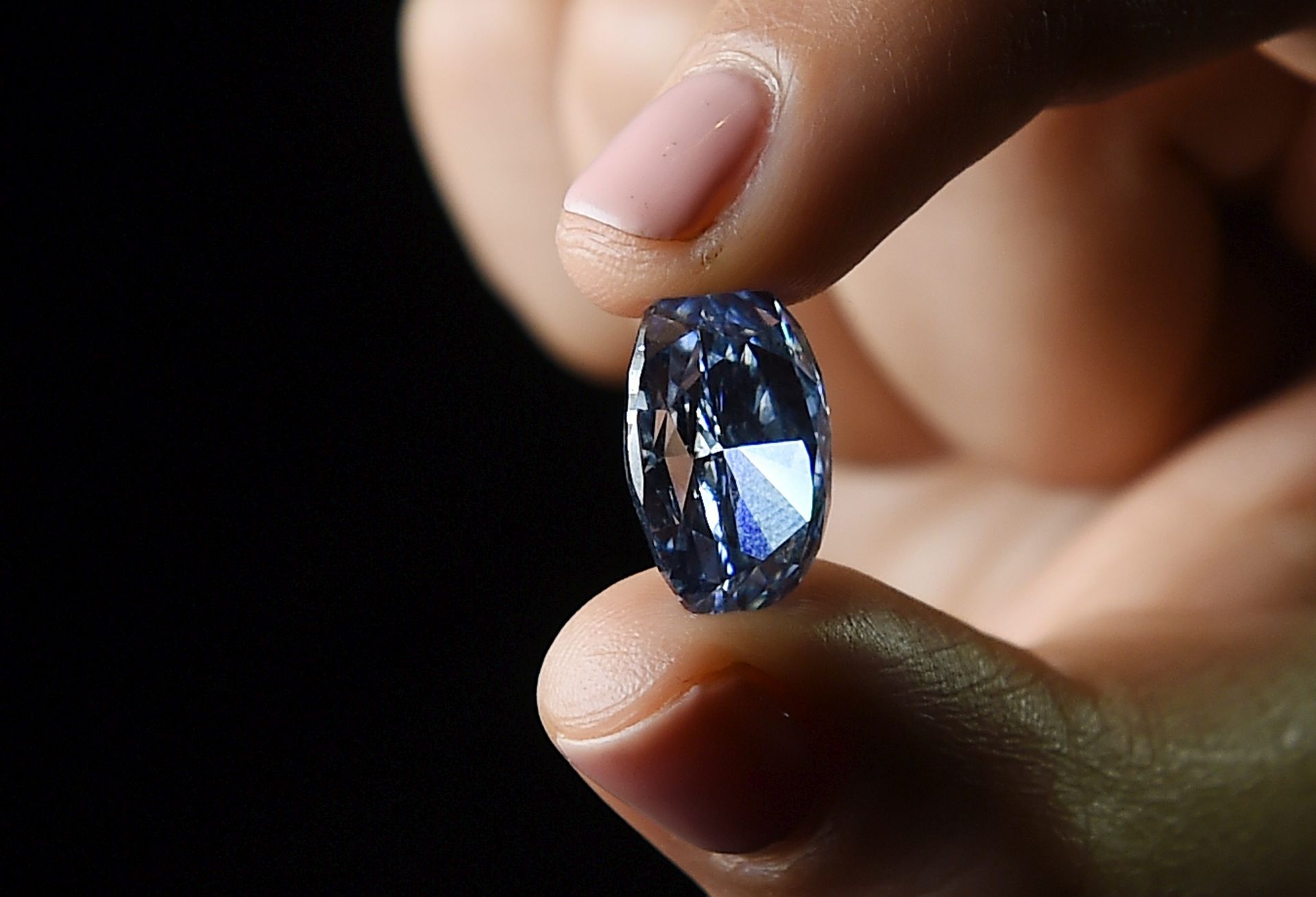 epa05212530 A Sotheby's staff holds the DeBeers Millennium Jewel 4 at Sotheby's auction house in London, Britain, 15 March 2016. The rare 10.10 carat oval internally flawless fancy vivid blue diamond is to lead Sotheby's Hong Kong spring sale on 05 April 2016. It is the largest oval vivid blue diamond ever to appear at auction and is estimated to fetch 30-35 million US dollars (about 27-32 million EUR).  EPA/ANDY RAIN