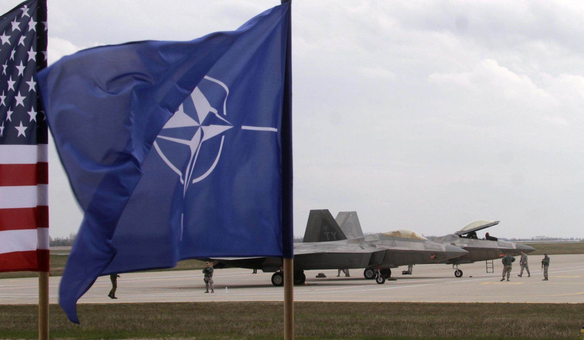 epa05280288 The flags of the USA and NATO fly in front of fifth-generation F-22 Raptor jets at Siauliai Air Base, Lithuania, 27 April 2016. Two US Air Force F-22 Raptors fighter jets arrived at Siauliai Air Base Air Base as support for regional security. The Lockheed Martin F-22 Raptor is a stealth fifth-generation tactical military jet developed for the United States Air Force (USAF), claimed to be the most advanced fighter in service.  EPA/VALDA KALNINA