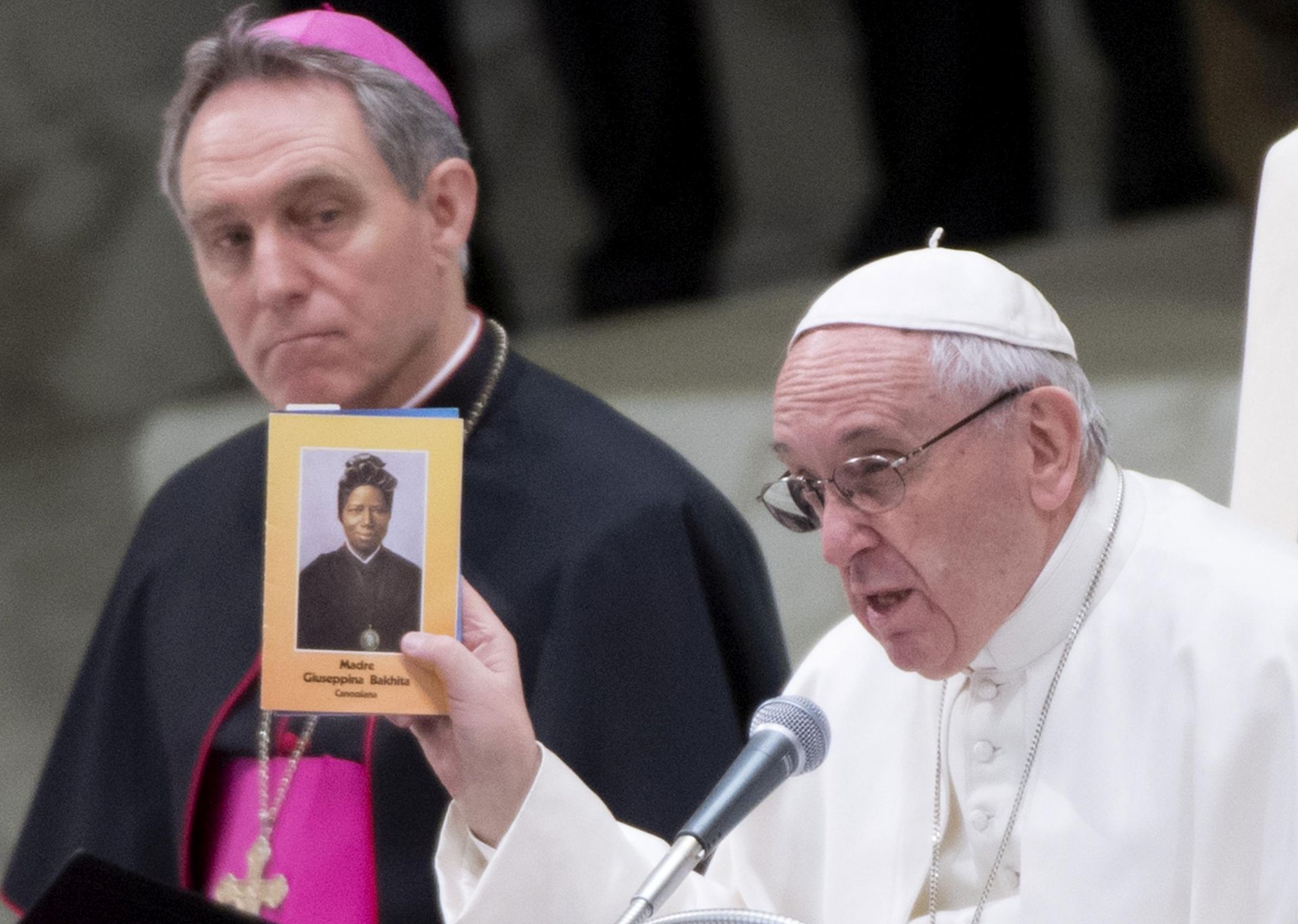 epa05777714 Pope Francis holds up an image of Saint Josephine Bakhita on the day of her Feast during his weekly Wednesday General Audience in Nervi Hall at the Vatican, 8 February 2017.  Born around 1869 in the Darfur region of Sudan, she was kidnapped by Arab slave traders sometime in February 1877. For over 12 years she was bought, sold and given away over a dozen times.  EPA/ANSA/CLAUDIO PERI