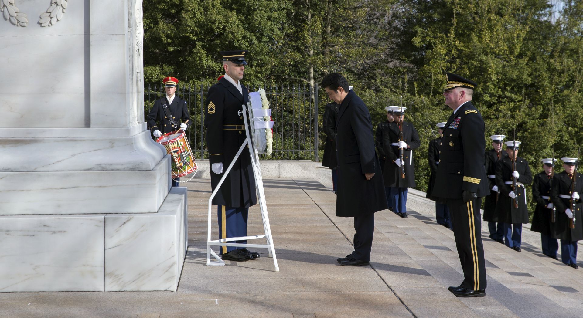 epa05783237 Prime Minister of Japan Shinzo Abe (C) bows as he participates in a wreath laying ceremony at the Tomb of the Unknown Soldier at Arlington National Cemetery in Arlington, Virginia, USA, 10 February 2017. Prime Minister Abe will meet with US President Donald J. Trump later in the day at the White House.  EPA/SHAWN THEW