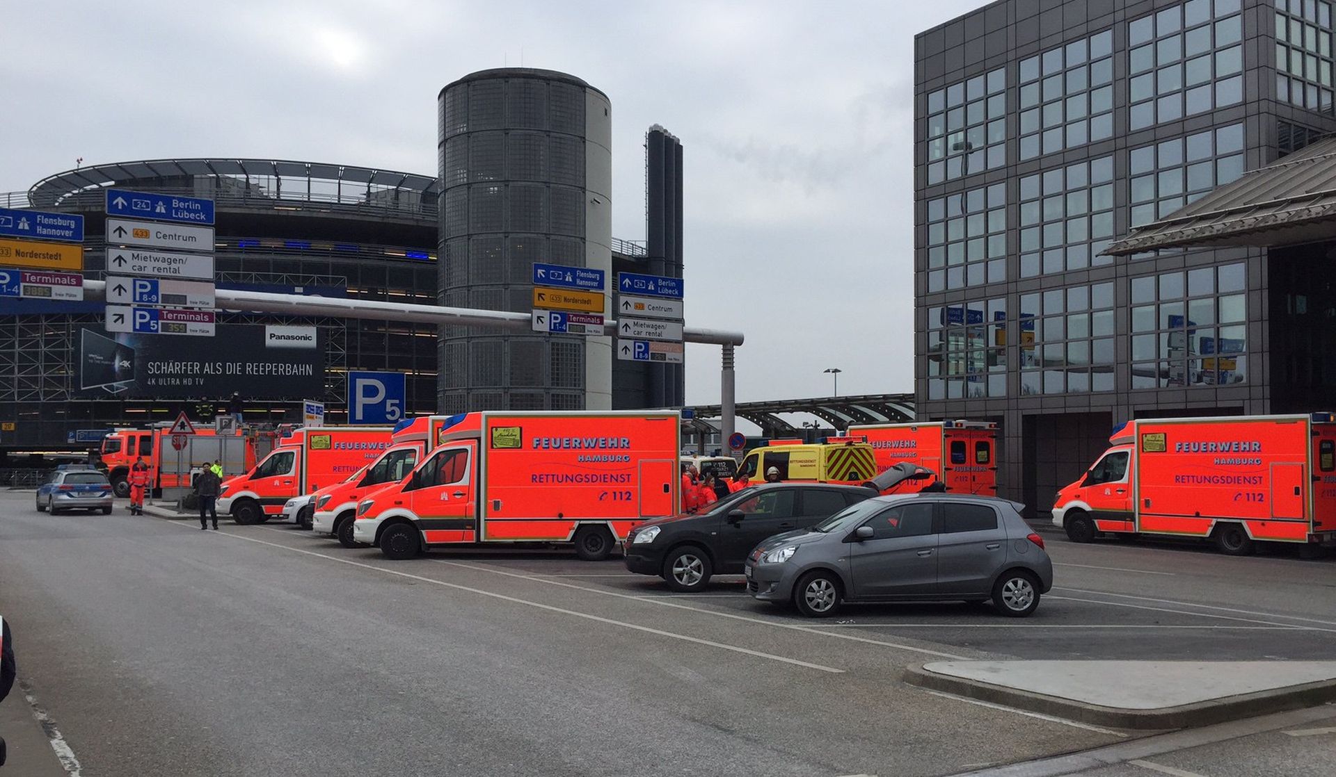 epa05787635 Ambulance and firefighter cars are parked in front of the airport of Hamburg, Germany 17 February 2017. The Hamburg airport has been temporarily evacuated after people reported suffering from breathing difficulties following an apparent gas leak.  EPA/LARS EBNER