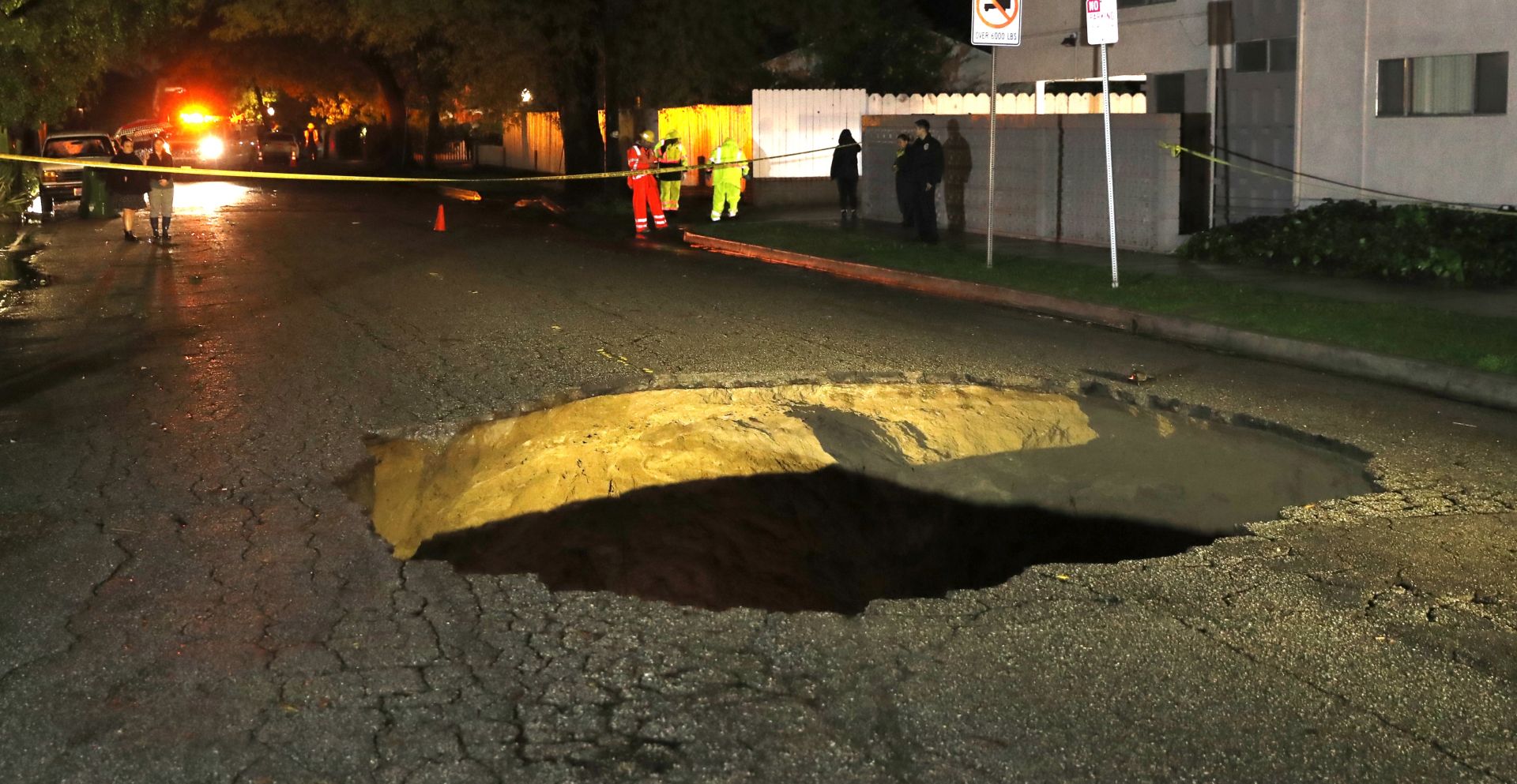 epa05801117 Emergency personnel stand near a sinkhole that opened up on Laurel Canyon Boulevard in Studio City, California, USA, 17 February 2017 and in which two cars were trapped.  A strong atmospheric river rain storm is pounding southern California causing flooding and falling trees which has resulted in two deaths.  EPA/MIKE NELSON