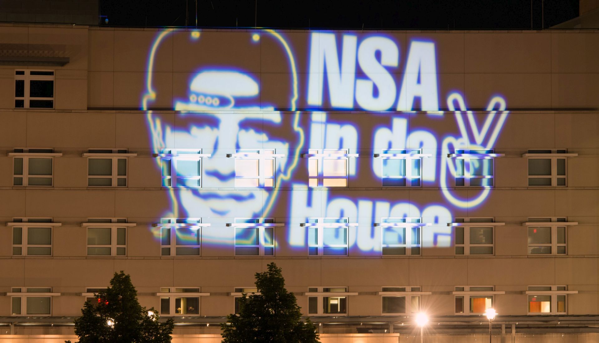 epa04322131 An image with the slogan 'NSA in da House' (National Security Agency in the house) and a stylized victory sign are projected, for several minutes, on the outside of the US embassy in Berlin, Germany, 19 July 2014, during an art event by German light artist Oliver Bienkowski. Germany has called on Washington to end its spying on Europe's biggest economy after relations between the two nations plunged to a new low in the wake of allegations of US espionage in the nation. Berlin expelled the US top intelligence officer in Germany amid claims that two German officials - one working for the domestic secret service (BND) and the other for the Defence Ministry - had handed over sensitive material to Washington.  EPA/SOEREN STACHE