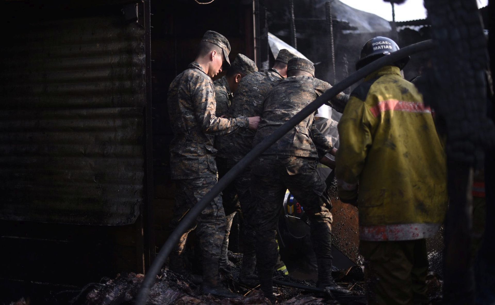 epa05218568 Guatemalan firefighters and soldiers work at the site after putting out the fire at La Termita local market in Guatemala City, Guatemala, 18 March 2016. At least two children died due to the fire that also caused lost of large amount of goods, authorities said.  EPA/SANTIAGO BILLY