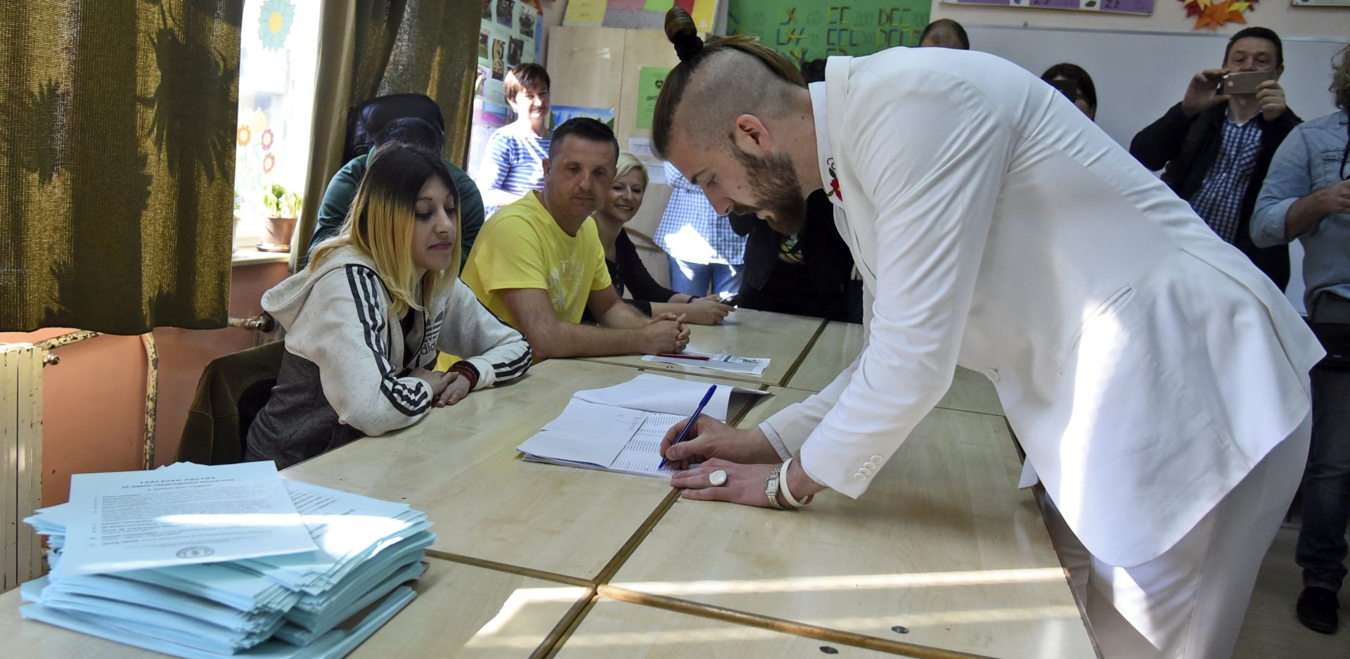 epa05884145 Independent presidential candidate Luka Maksimovic (R), also known in his satirical role of Ljubisa Preletacevic 'Beli' (The White), signs in a list at a polling station in Mladenovac, Serbia, 02 April 2017. Eleven candidates are running for the office of the President of the republic of Serbia, the term of office that will last five years and begin from the day of taking of the oath before the National Assembly.  EPA/STR