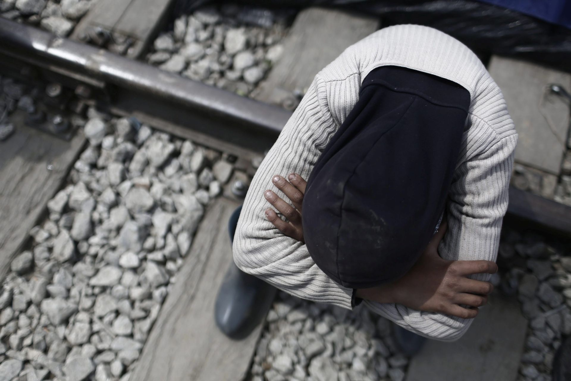 epa05254424 A refugee sits on train tracks during a protest demanding the opening of the borders at the border line between Greece and FYROM, at the refugee camp of Idomeni, 11 April 2016. Thousands of refugees are stuck in Greece following the closure of the borders of the Balkan route and after the implementation of the migration agreement between the European Union (EU) and Turkey.  EPA/KOSTAS TSIRONIS