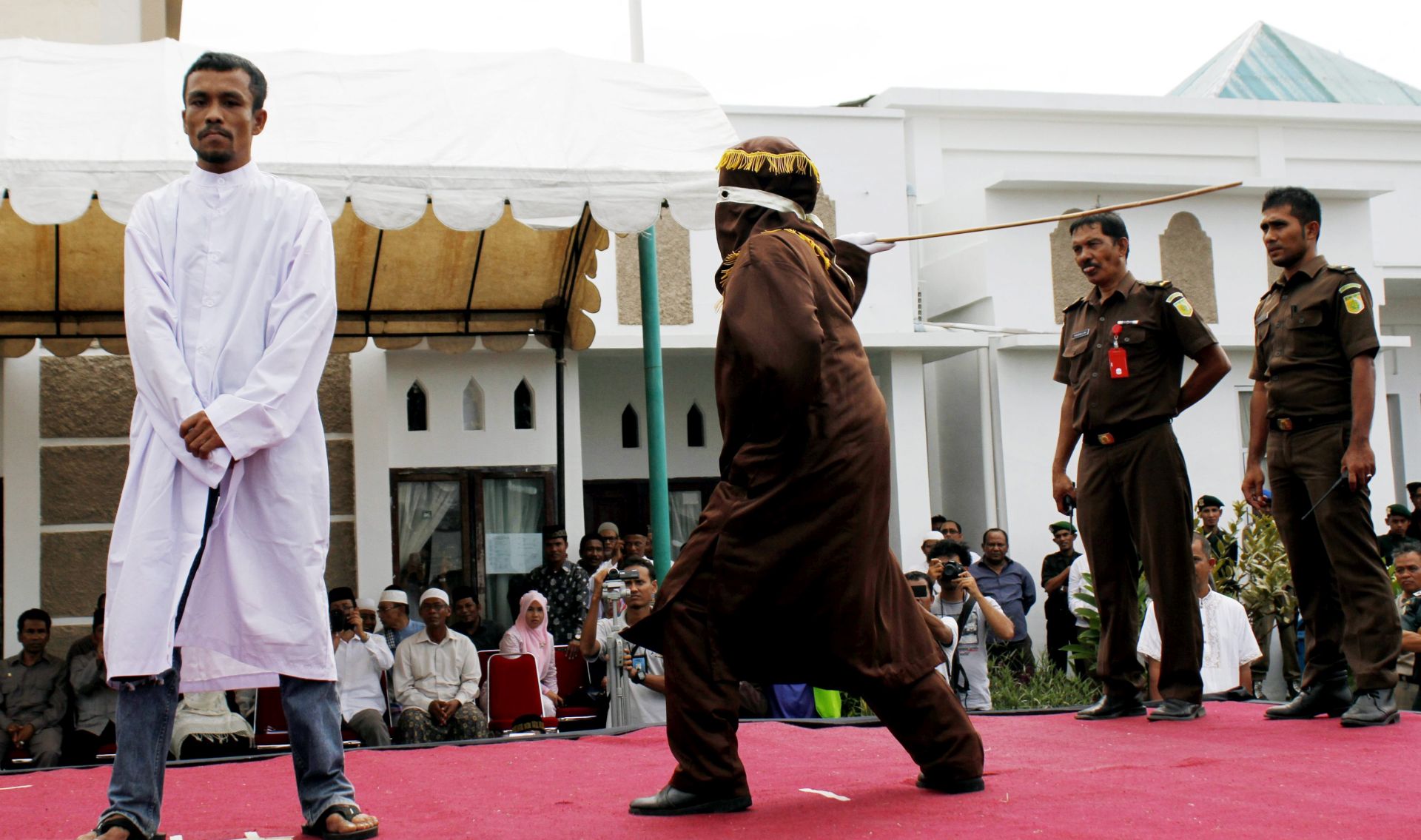 epa04429686 A gambler is publicly caned for breaking the Shariah Law outside of Al Makmur Mosque in Lampriet, Banda Aceh, Indonesia, 03 October 2014. Aceh is the only province in Indonesia that implements Syariah Law as a public law, and caning is one of the punishments. Amnesty International criticized the law 'an enormous step backwards for human rights.' Amnesty said at least 156 people have been caned in Aceh since 2010 for offences such as gambling, mixing with the opposite sex and selling food during the Ramadan fasting month.  EPA/GIBRAN