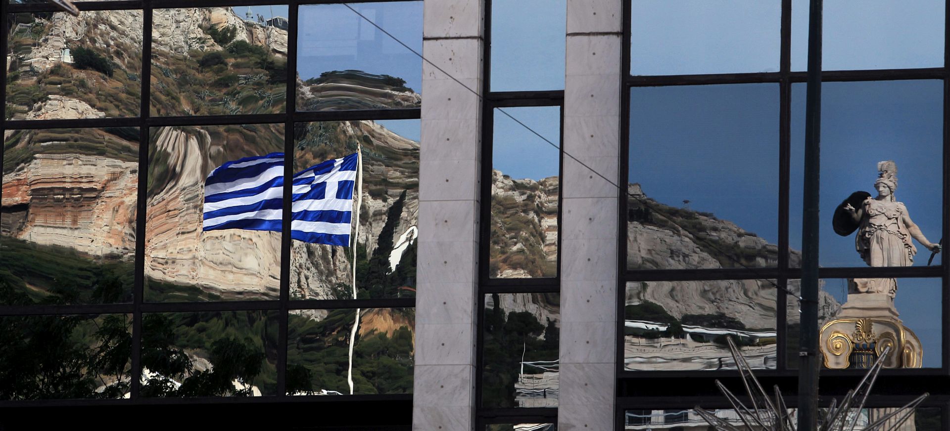 epa04779332 A sculpture of ancient greek goddess Athena and greek flags are reflected on a building in central Athens, Greece, on 01 June 2015. According to reports deliberations on issues regarding the Greek economy continue at the Brussels Group, with some saying a gradual deal on a technical level is considered possible with discussions expected to continue 01 June.  EPA/SIMELA PANTZARTZI