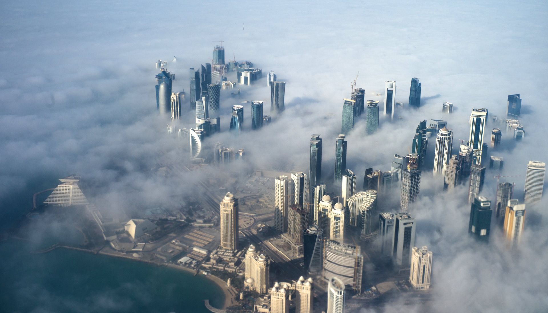 epa06011227 (FILE) - An aerial view of high-rise buildings emerging through fog covering the skyline of Doha, as the sun rises over the city, in Doha, Qatar, 15 February 2014 (reissued 05 June 2017). According to media reports, Egypt, Saudi Arabia, Bahrain and the United Arab Emirates cut off diplomatic ties with Qatar on 05 June 2017, accusing Qatar of supporting terrorism.  EPA/YOAN VALAT