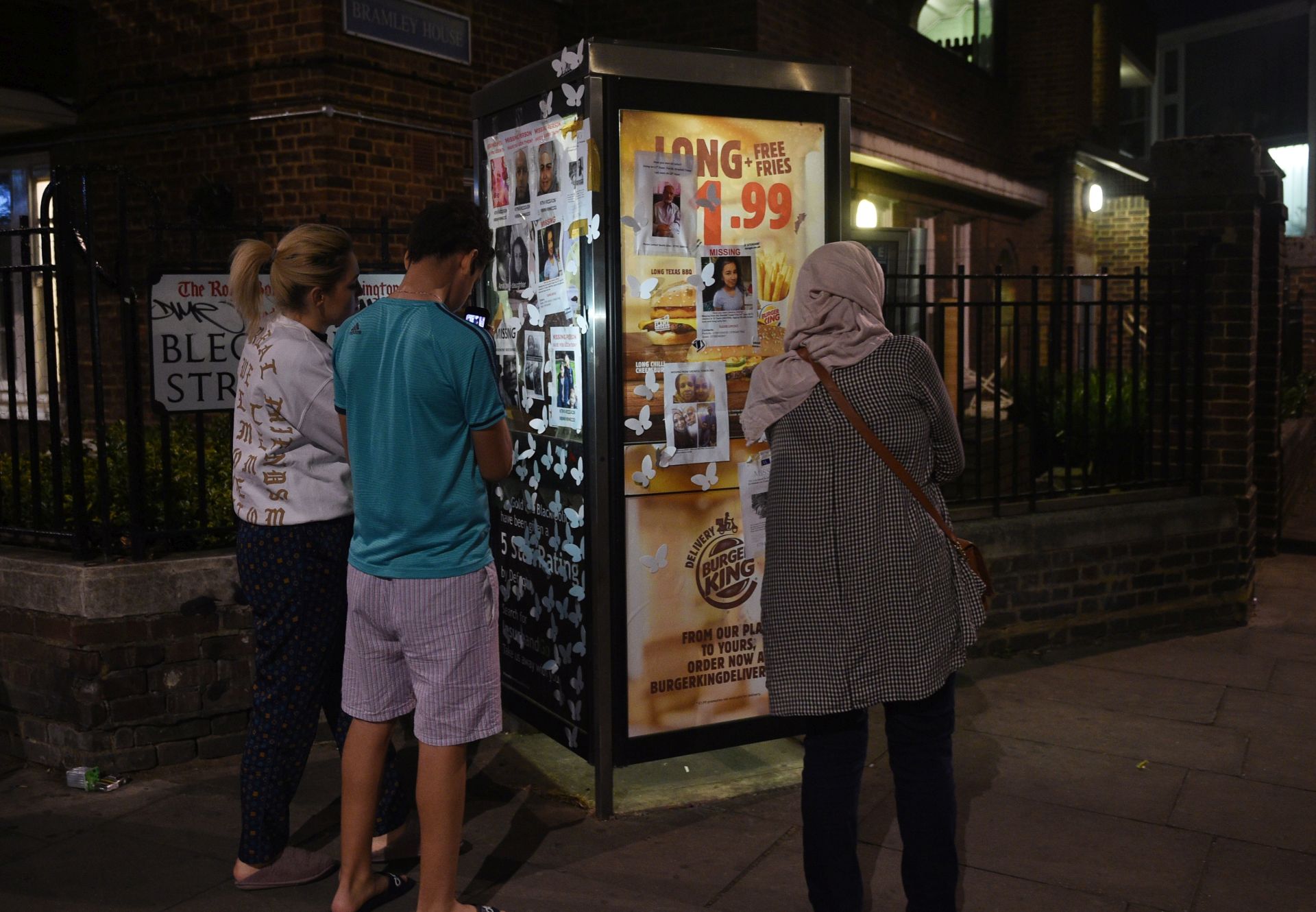 epa06030595 People look at photographs of missing persons in a phone box near where the fire broke out at Grenfell Tower, a 24-storey apartment block in North Kensington, London, Britain, 15 June 2017. London Fire Brigade (LFB), said it took 40 fire engines and 200 firefighters to put out the blaze that broke out at around 1:00 am GMT on 14 June, and which took more than 24 hours to bring under control. According to reports, 12 people were confirmed dead in the fire and the cause of the blaze remains unknown.  EPA/FACUNDO ARRIZABALAGA