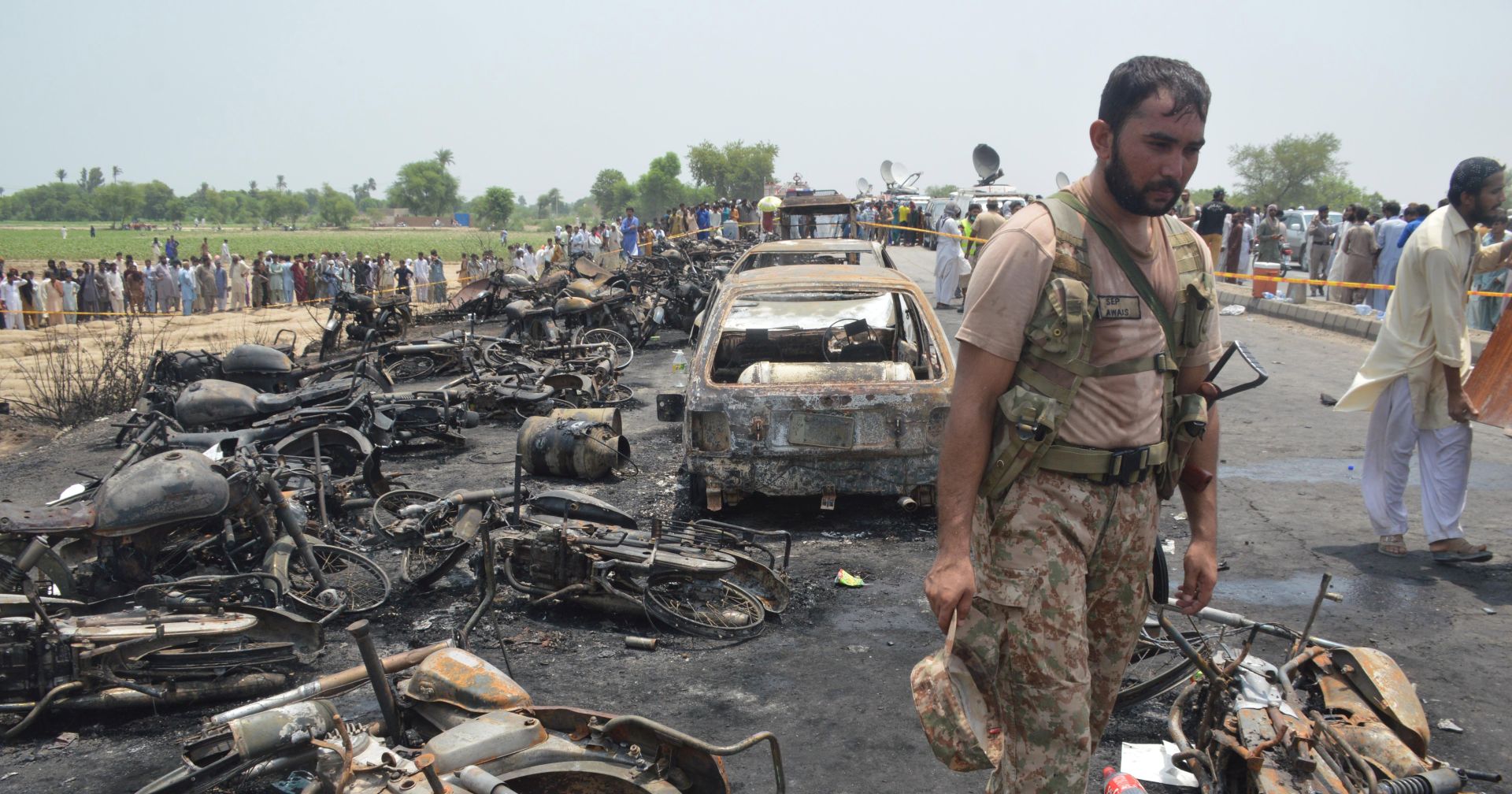 epa06049178 A Pakistani Army soldier stands guard amidst the burnt vehicles at the scene of an Oil tanker accident on the outskirts of Bahawalpur, Pakistan, 25 June 2017. At least 123 people were killed and 80 injured when an Oil tanker exploded as people gathered to collect oil from the tanker that overturned on a highway near Bahawalpur.  EPA/FAISAL KAREEM