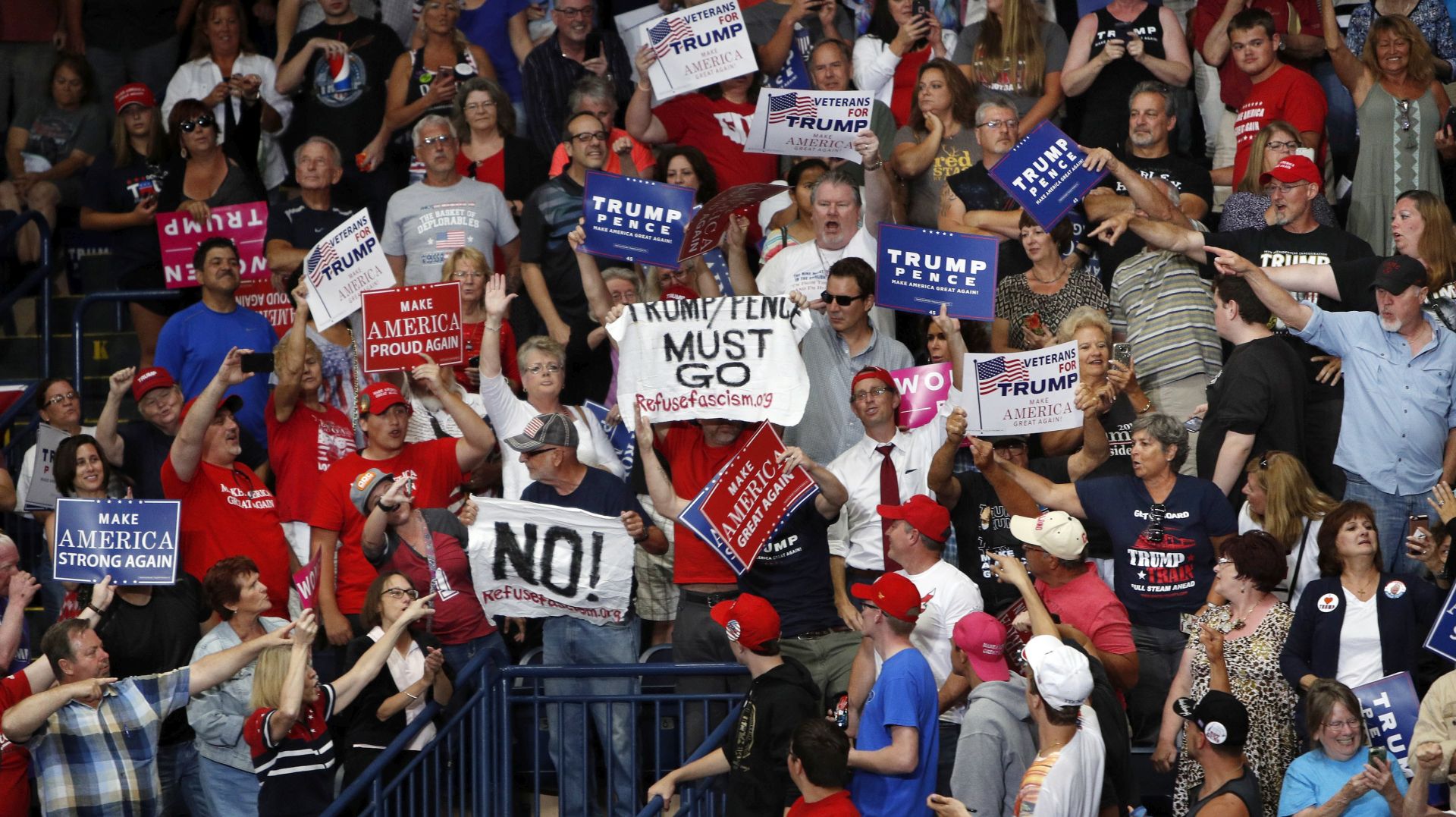 epa06109746 Protesters in the crowd (C) hold signs before being removed by the security as US President Donald J. Trump (not pictured) speaks at a 'Make America Great Again' rally at the Covelli Centre in Youngstown, Ohio, USA, 25 July 2017. Protest banners read 'TRUMP/PENCE MUST GO' and 'NO!'.  EPA/DAVID MAXWELL